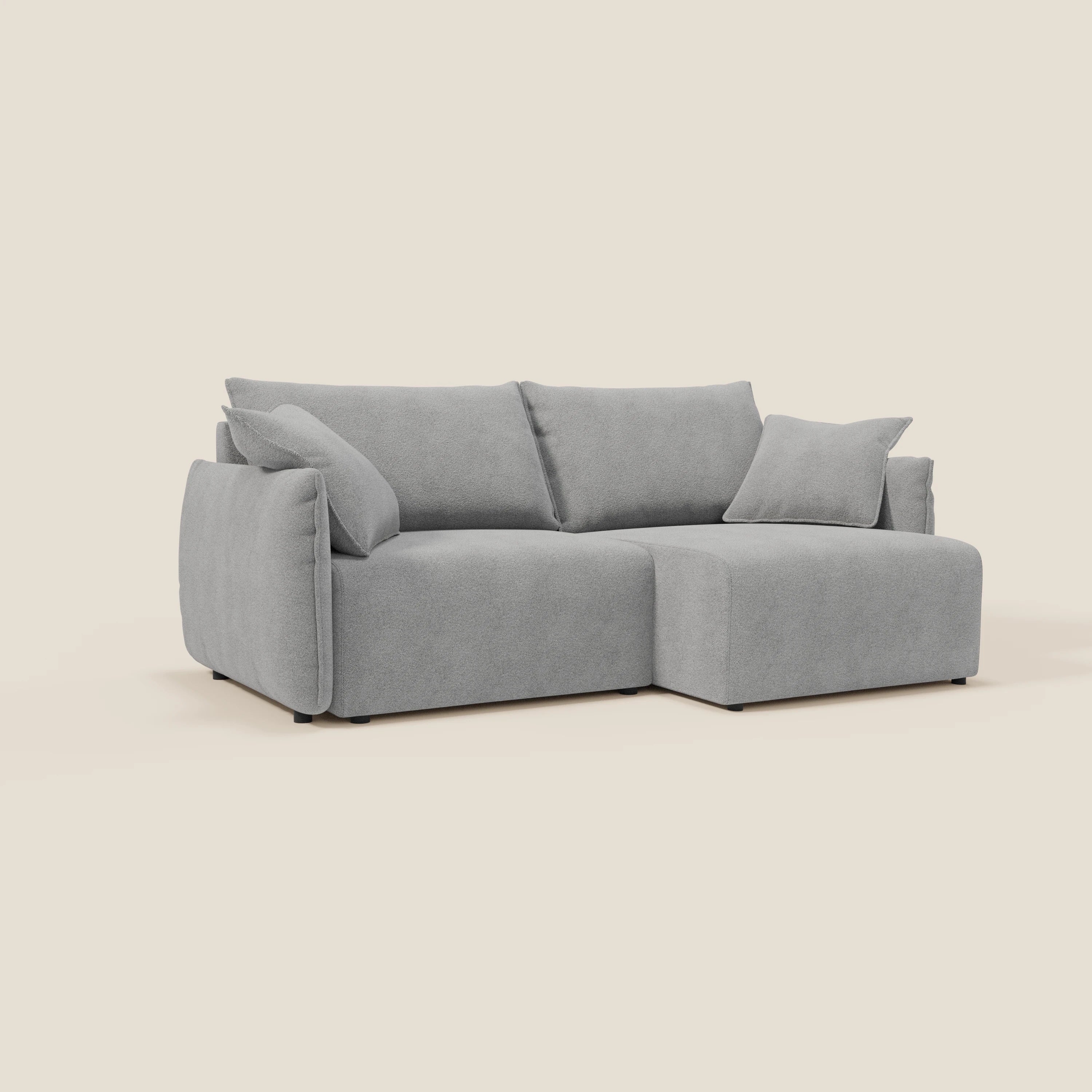 Un moderno divano Flexar con sedute allungabili e schienale in piuma in morbido bouclé impermeabile T07 grigio di Divani.Store, con chaise longue destra, cuscini in feltro e cuscino coordinato, su sfondo bianco sporco.