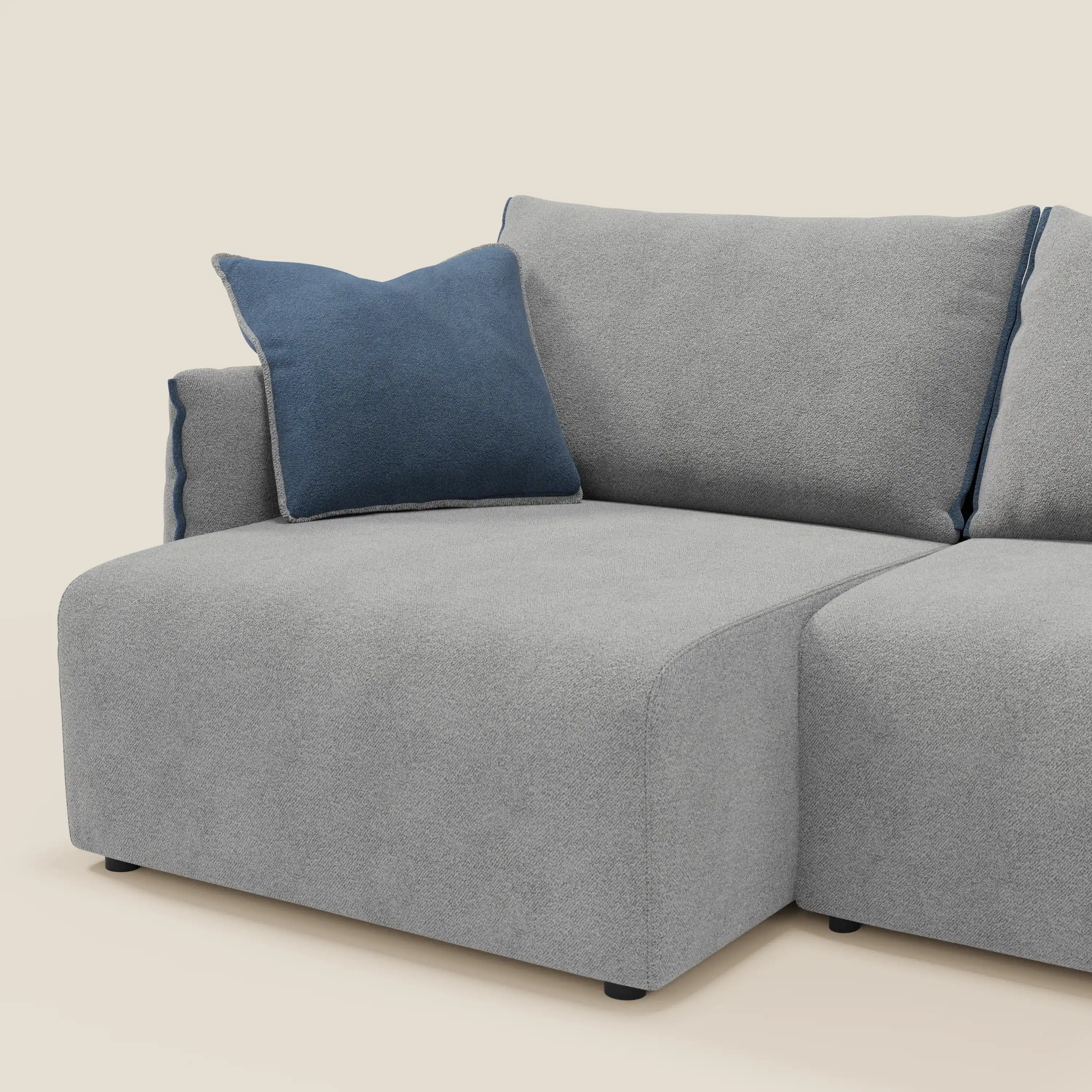 Il divano Flexar di Divani.Store in T07 grigio-blu bouclé è caratterizzato da sedute allungabili, piuma schienale, cuscino d'accento blu, linee curve, morbido tessuto impermeabile e piedini neri bassi con chaise lounge a sinistra.
