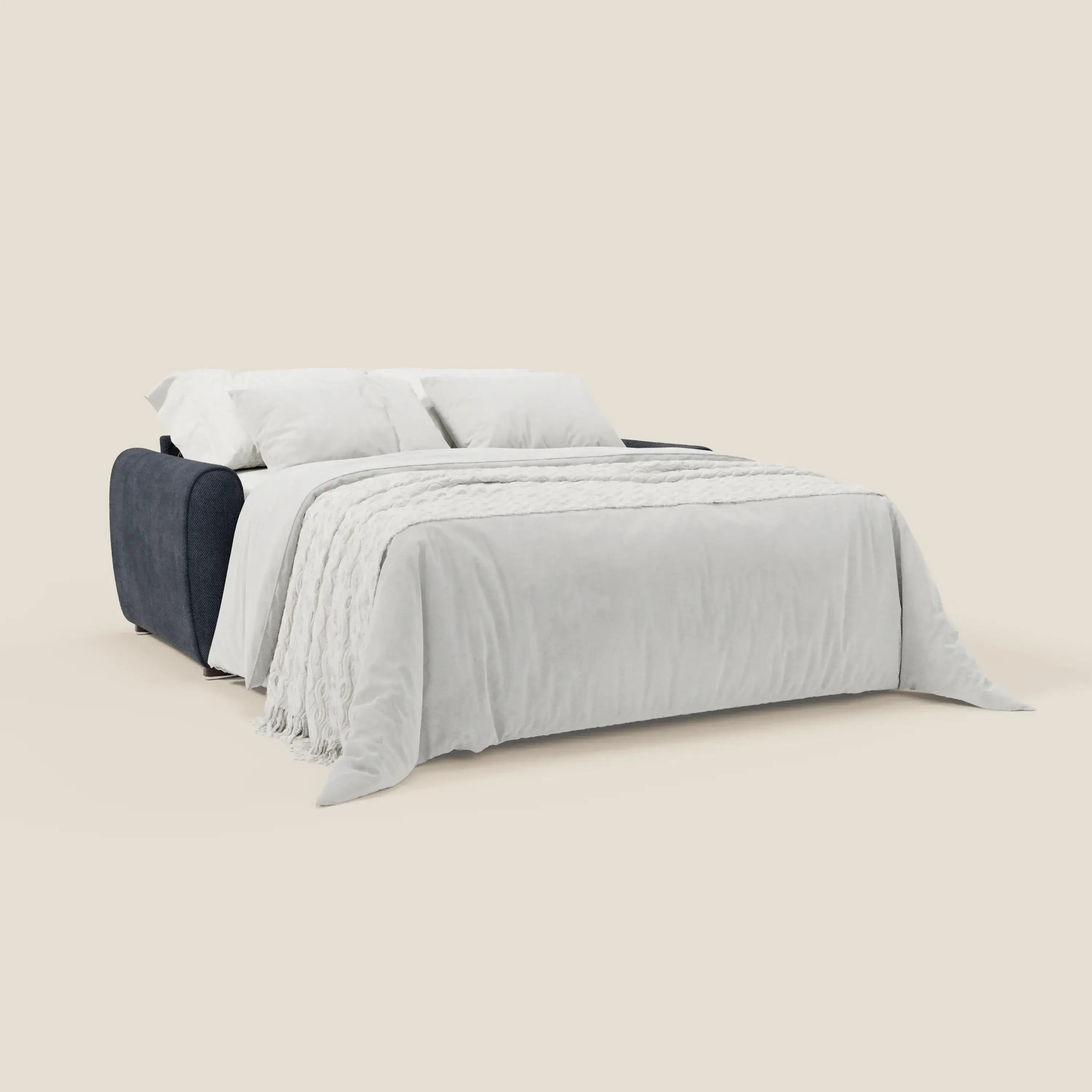 Il Kaleo Divano letto moderno di Divani.Store è caratterizzato da tessuto impermeabile T26 dark navy, fianchi e schienale imbottiti, materasso ad alta densità da 17 cm ed è presentato come letto con lenzuola e cuscini bianchi su sfondo beige tinta unita.