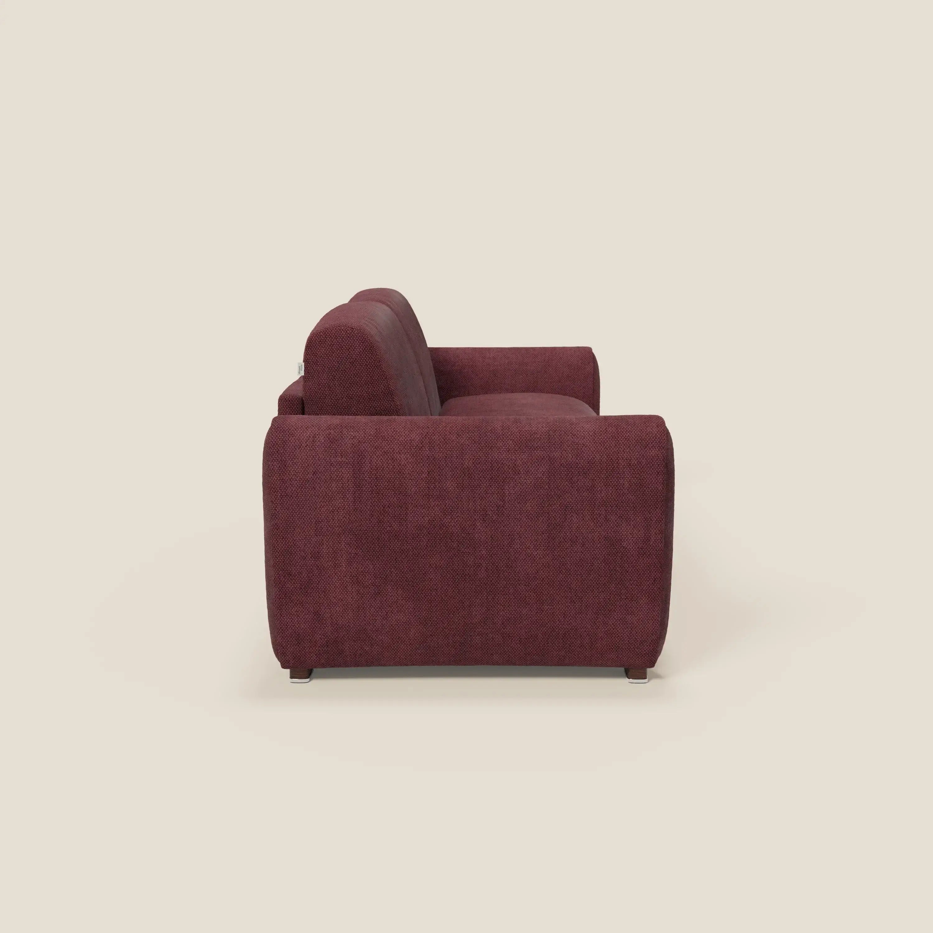 Vista laterale del divano letto moderno Kaleo di Divani.Store in raffinato tessuto impermeabile T26 bordeaux prugna, con braccioli larghi, design a cassettoni, materasso H17 cm ad alta densità e gambe corte per un look di basso profilo su uno sfondo bianco sporco.