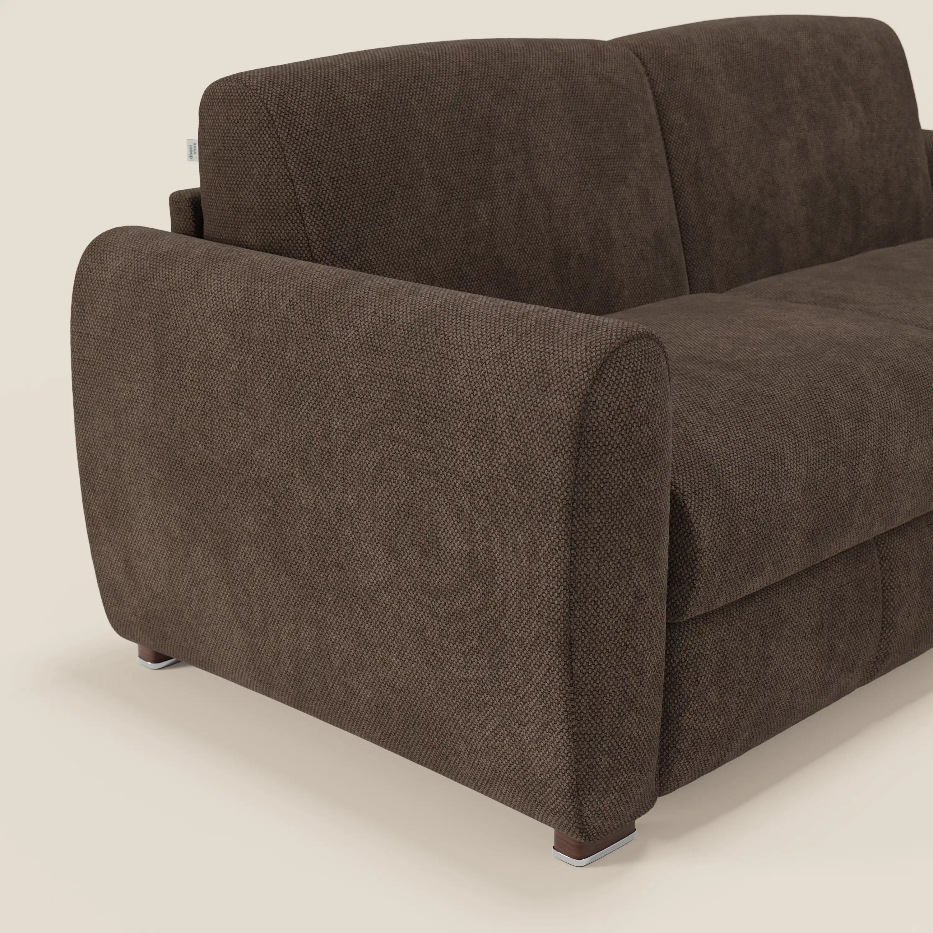 Una vista angolata e ravvicinata del divano letto moderno Kaleo di Divani.Store in tessuto impermeabile T26 marrone mostra l'ampio bracciolo arrotondato, l'imbottitura testurizzata, i piedini metallici corti e lo schienale parziale su uno sfondo beige chiaro.
