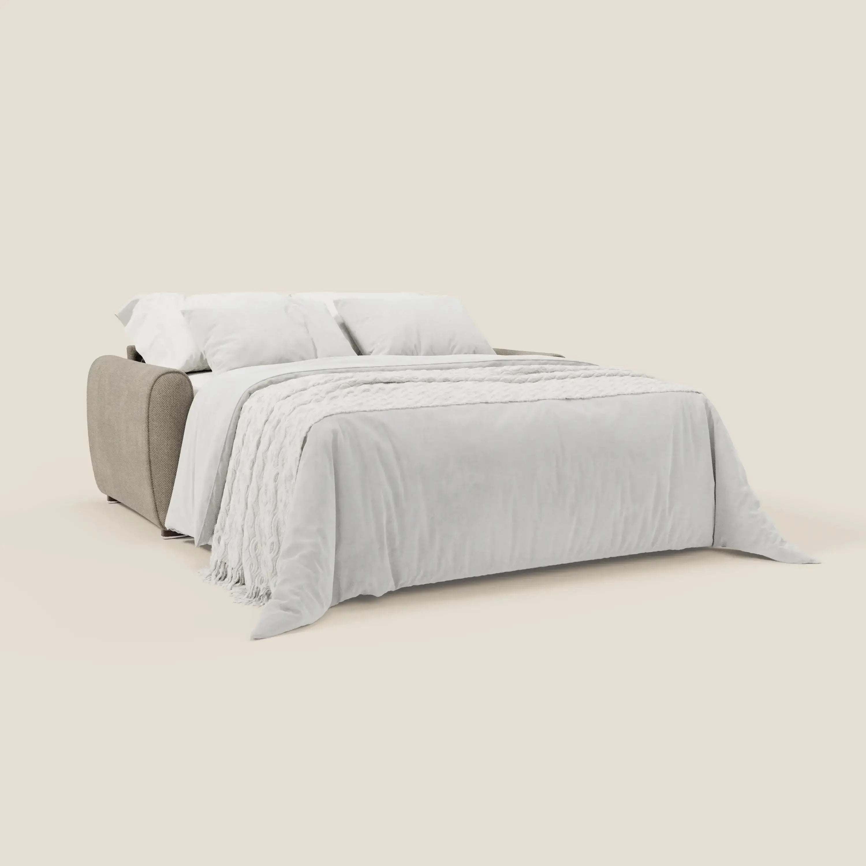 Il divano letto moderno Kaleo di Divani.Store, in tessuto impermeabile T26 tortora, si apre in un letto con materasso H17 cm, realizzato in modo ordinato con lenzuola bianche e una coperta strutturata, su uno sfondo beige tinta unita.