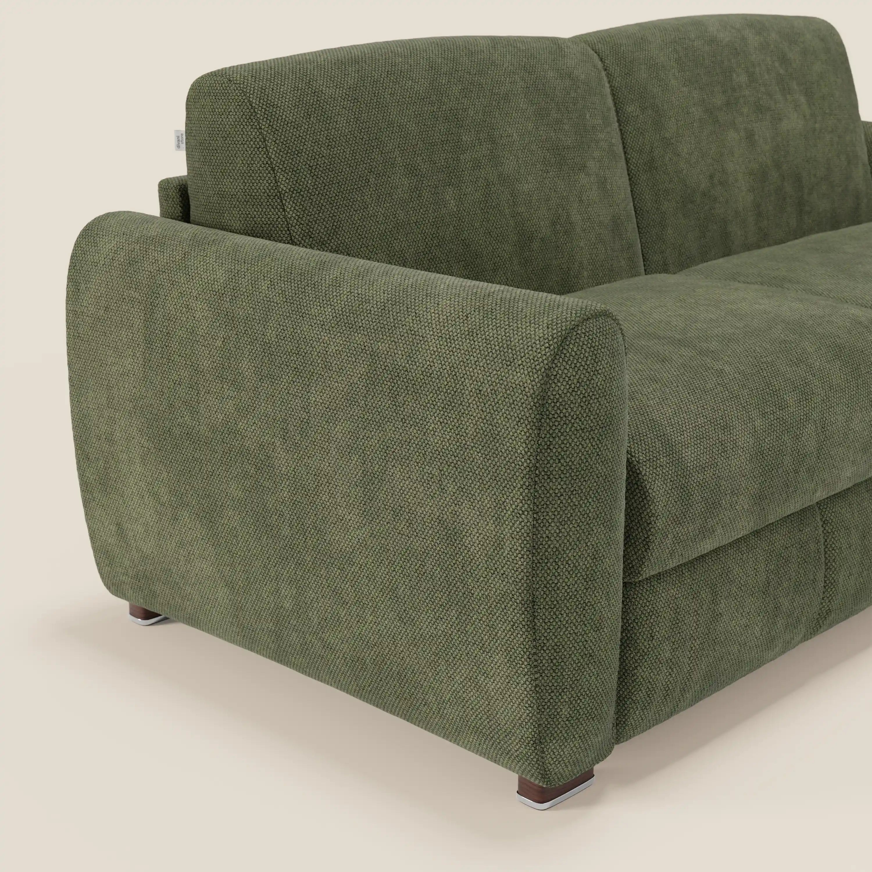 Un primo piano di Kaleo Divano letto moderno di Divani.Store, rivestito in raffinato tessuto impermeabile T26 verde muschio, mostra il bracciolo sinistro arrotondato e lo schienale su corte gambe quadrate in legno su uno sfondo chiaro.