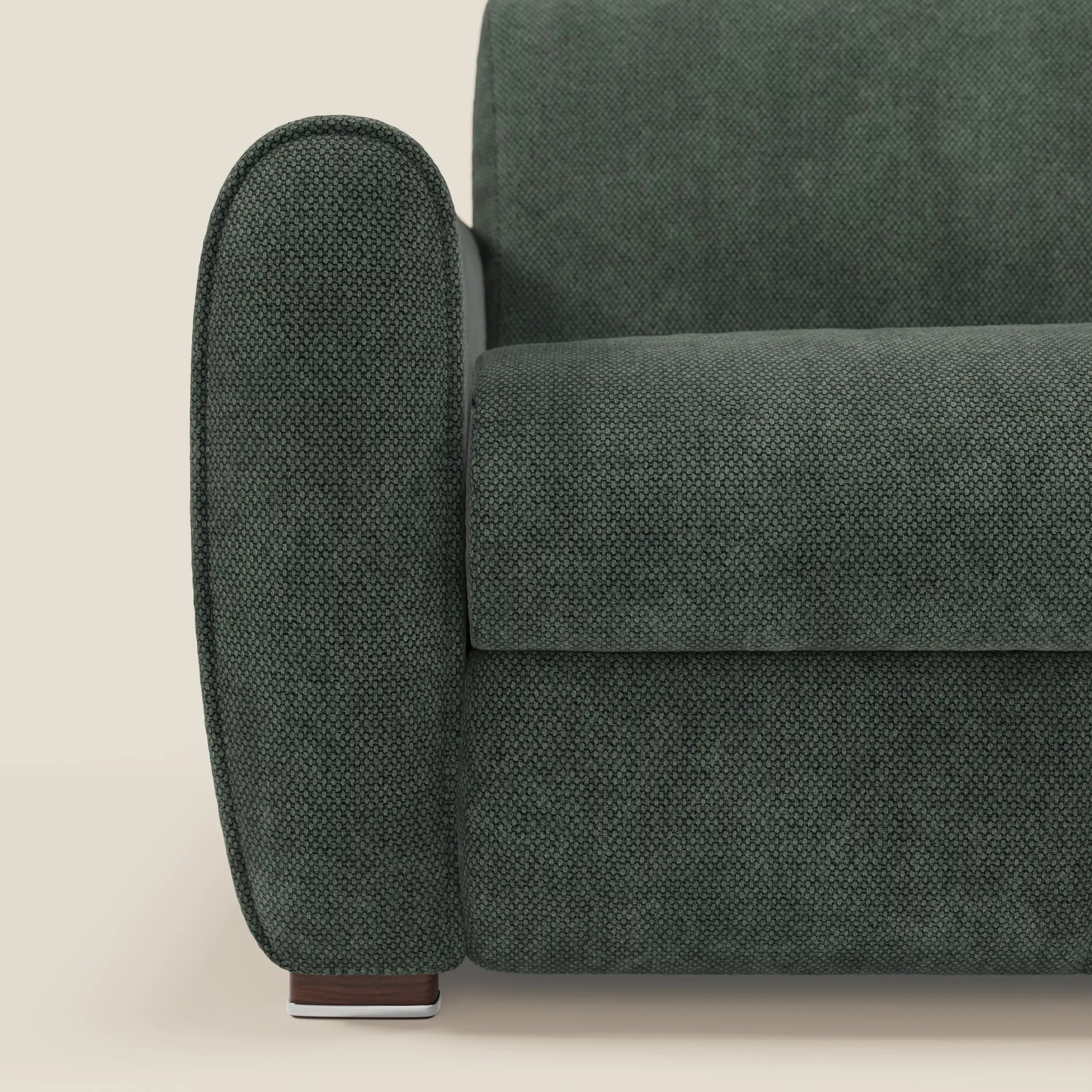 Primo piano del divano letto moderno Kaleo di Divani.Store in tessuto impermeabile T26 verde oliva. Mostra il bracciolo arrotondato, la seduta e lo schienale imbottiti e la piccola gamba in legno, ideale per gli amanti del design contemporaneo.