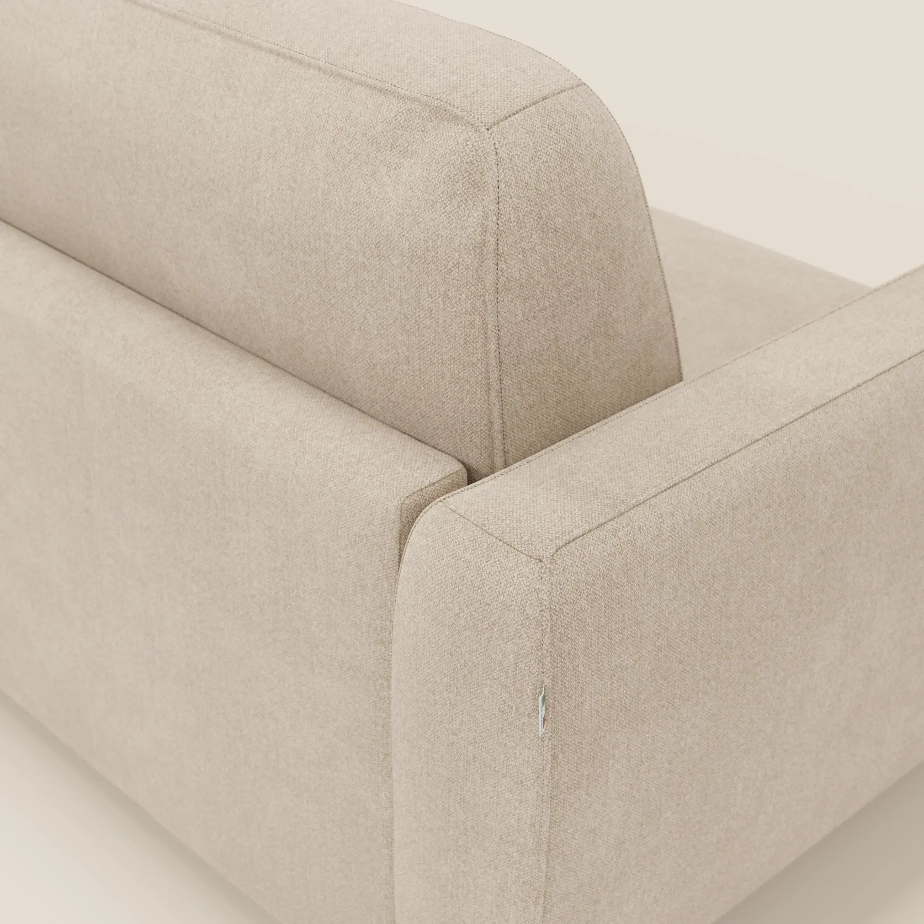 Un primo piano del divano letto sfoderabile Leonida di Divani.Store in tessuto Smacchiabile T23 beige, che mette in evidenza le linee pulite, le cuciture precise e il materasso H18 cm ad alta densità su uno sfondo neutro.