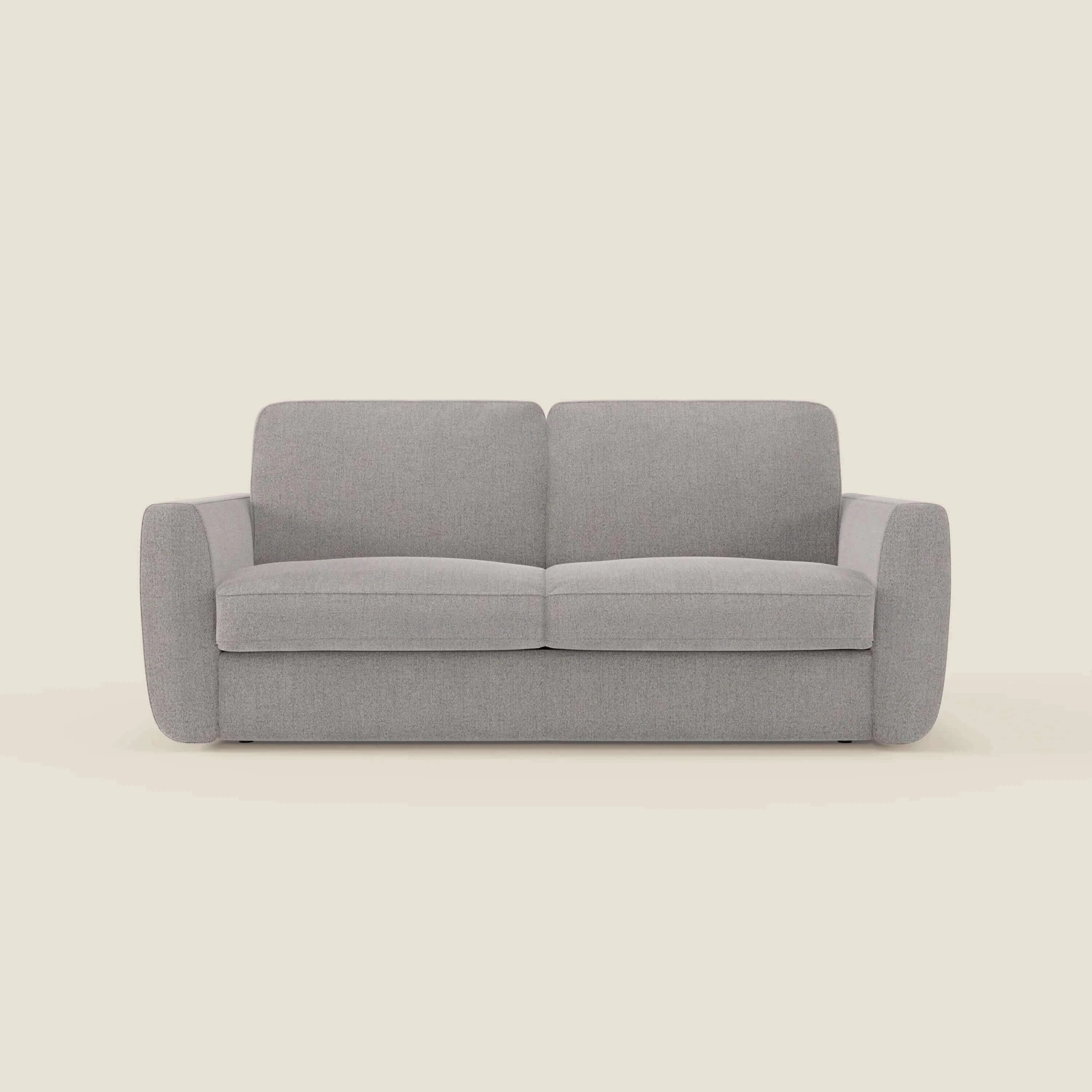 Il divano letto sfoderabile Leonida di Divani.Store in smacchiabile T23 grigio è caratterizzato da braccioli arrotondati, cuscini di schienale rettangolari e un design pulito e minimale senza gambe visibili, su uno sfondo beige chiaro.