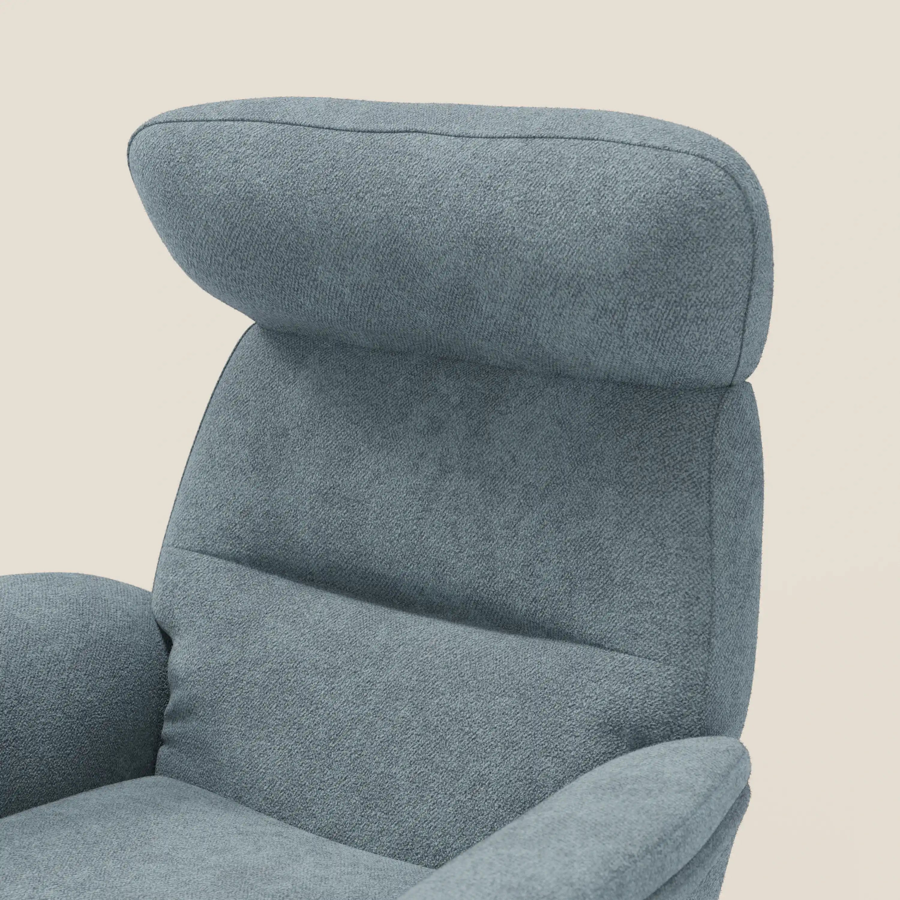 Primo piano della Poltrona relax reclinabile Lunor di Divani.Store, in tessuto bouclé impermeabile T07 carta da zucchero, con schienale alto e poggiatesta imbottito, braccioli curvi e pouf coordinato. Il fondo è in tinta unita beige chiaro.