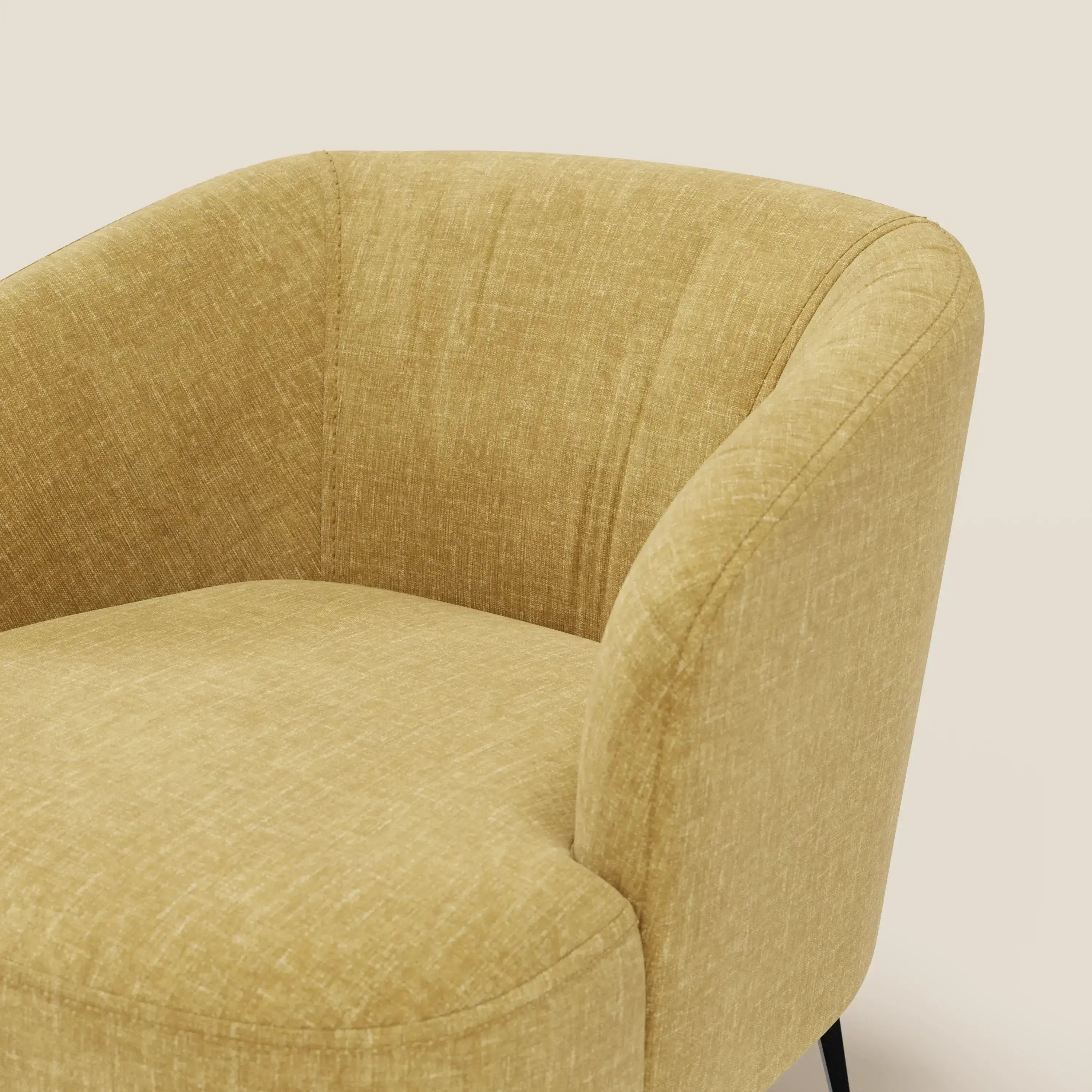 Un primo piano della poltroncina Renoa di Divani.Store, caratterizzata da braccioli arrotondati e tessuto antimacchia T24 giallo, evidenzia un comfort avvolgente. Sullo sfondo beige chiaro sono visibili solo la parte superiore e una sottile gamba in metallo nero.