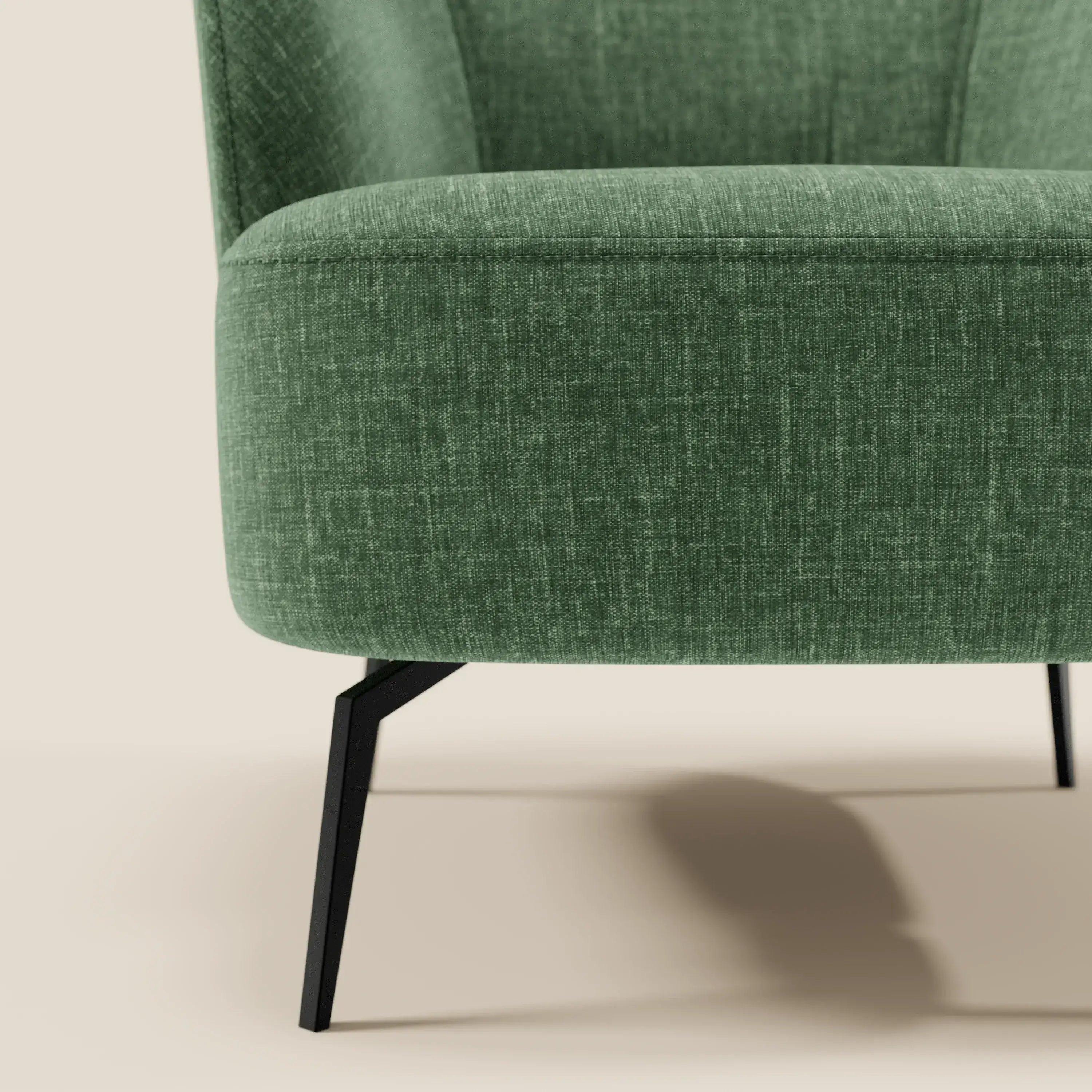 Primo piano della poltroncina Renoa dall'eleganza moderna in tessuto smacchiabile T24 verde oliva di Divani.Store, con tessuto verde testurizzato, gambe in metallo nero e design curvo su sfondo beige neutro.