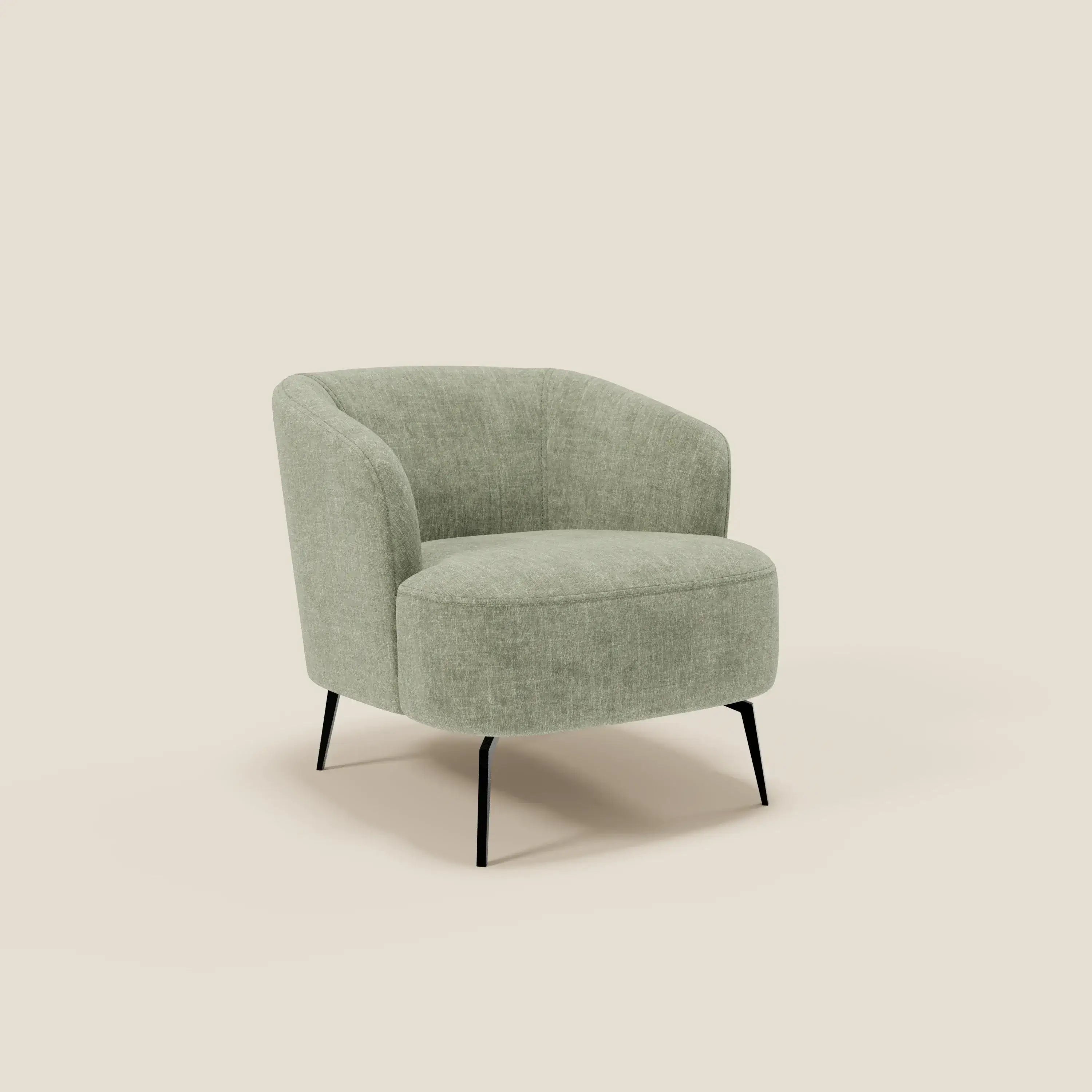 La poltroncina Renoa dall'eleganza moderna in tessuto smacchiabile T24 verde salvia di Divani.Store è caratterizzata da uno schienale e una seduta curvi, da un'imbottitura morbida e strutturata e da quattro sottili gambe in metallo nero, su sfondo beige.
