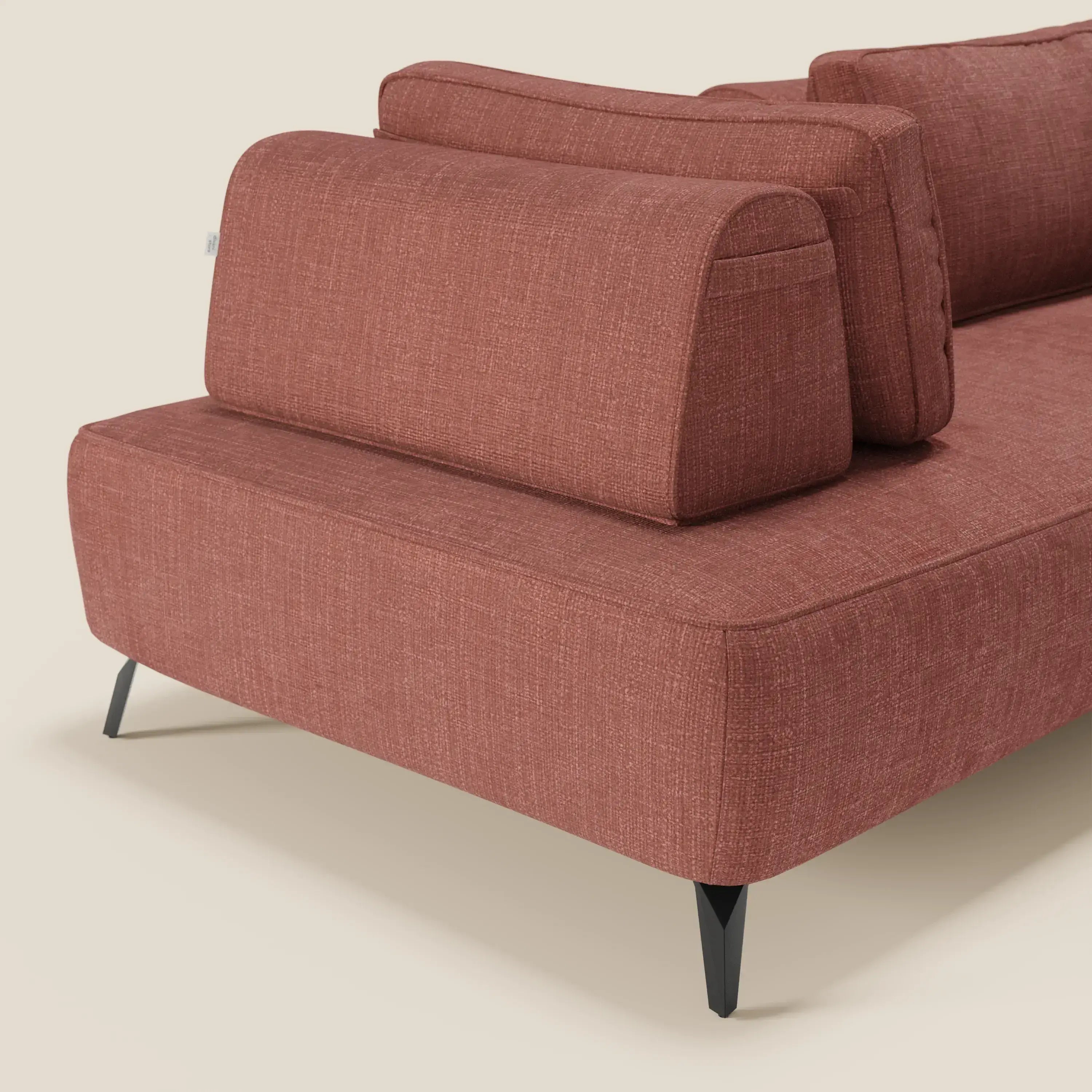 Un primo piano di Volta divano modulare con schienali mobili in tessuto ciniglia T06 corallo di Divani.Store: seduta e schienali fermi, gambe nere in metallo, design minimal dai bordi morbidi risaltano su sfondo beige.