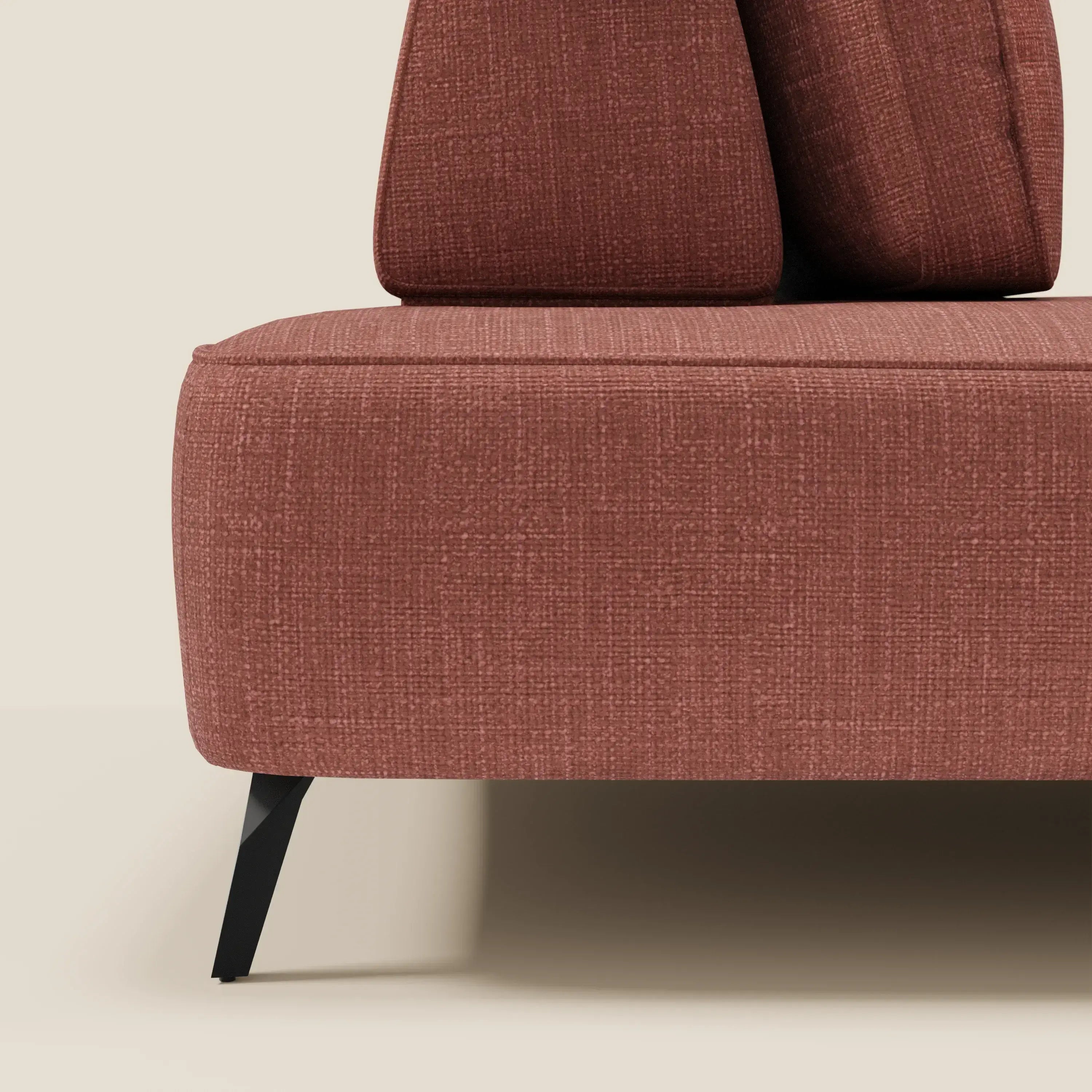 Primo piano del divano modulare Volta di Divani.Store, caratterizzato da tessuto raffinato ciniglia T06 corallo, schienali mobili, gambe angolari in metallo nero e cuscini geometrici su sfondo beige chiaro. Sono visibili solo parte della seduta e due cuscini.