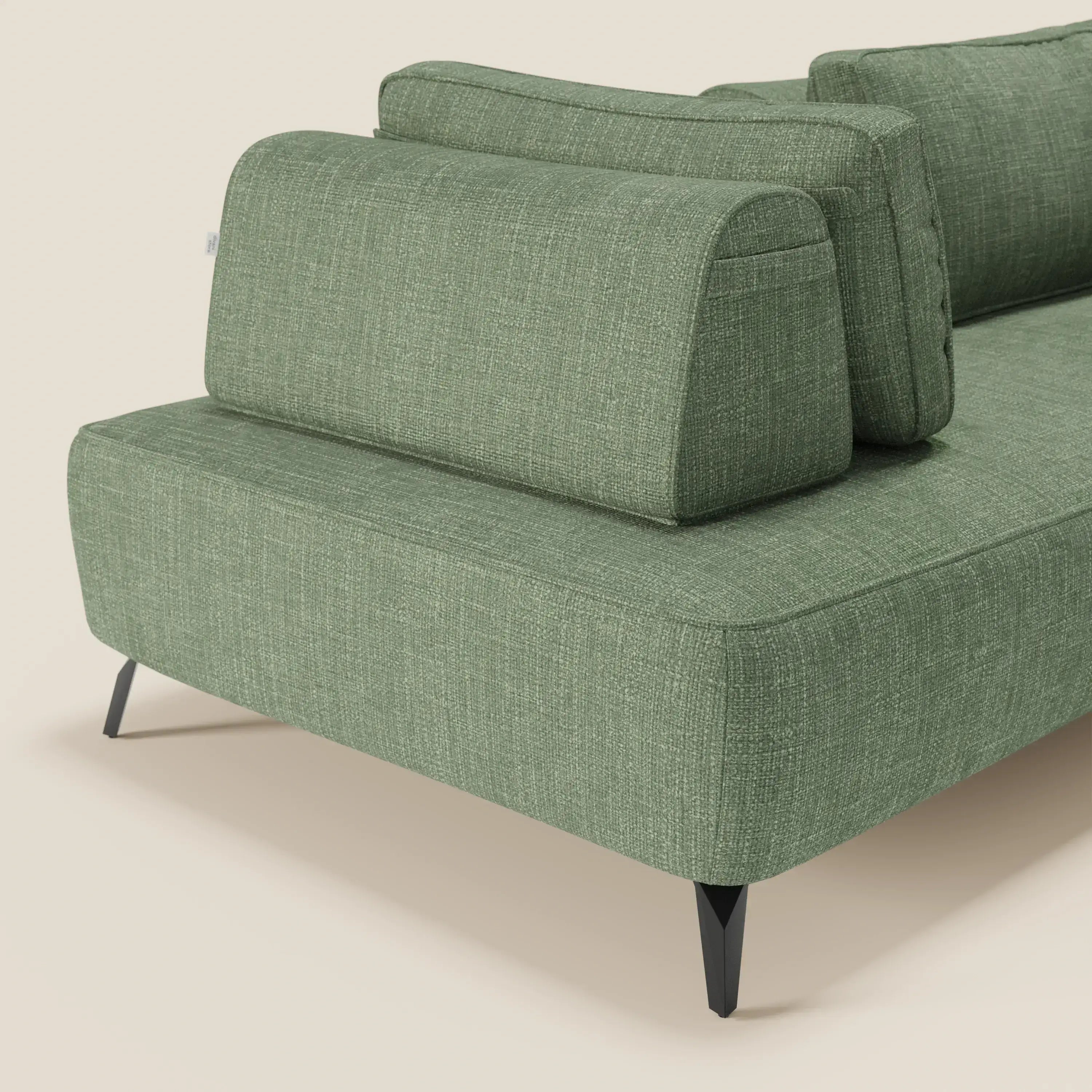 Un primo piano del divano modulare Volta con schienali mobili in raffinato tessuto ciniglia T06 verde di Divani.Store, con schienali imbottiti geometrici e gambe angolari nere, si staglia su uno sfondo beige semplice che ne evidenzia il design moderno.