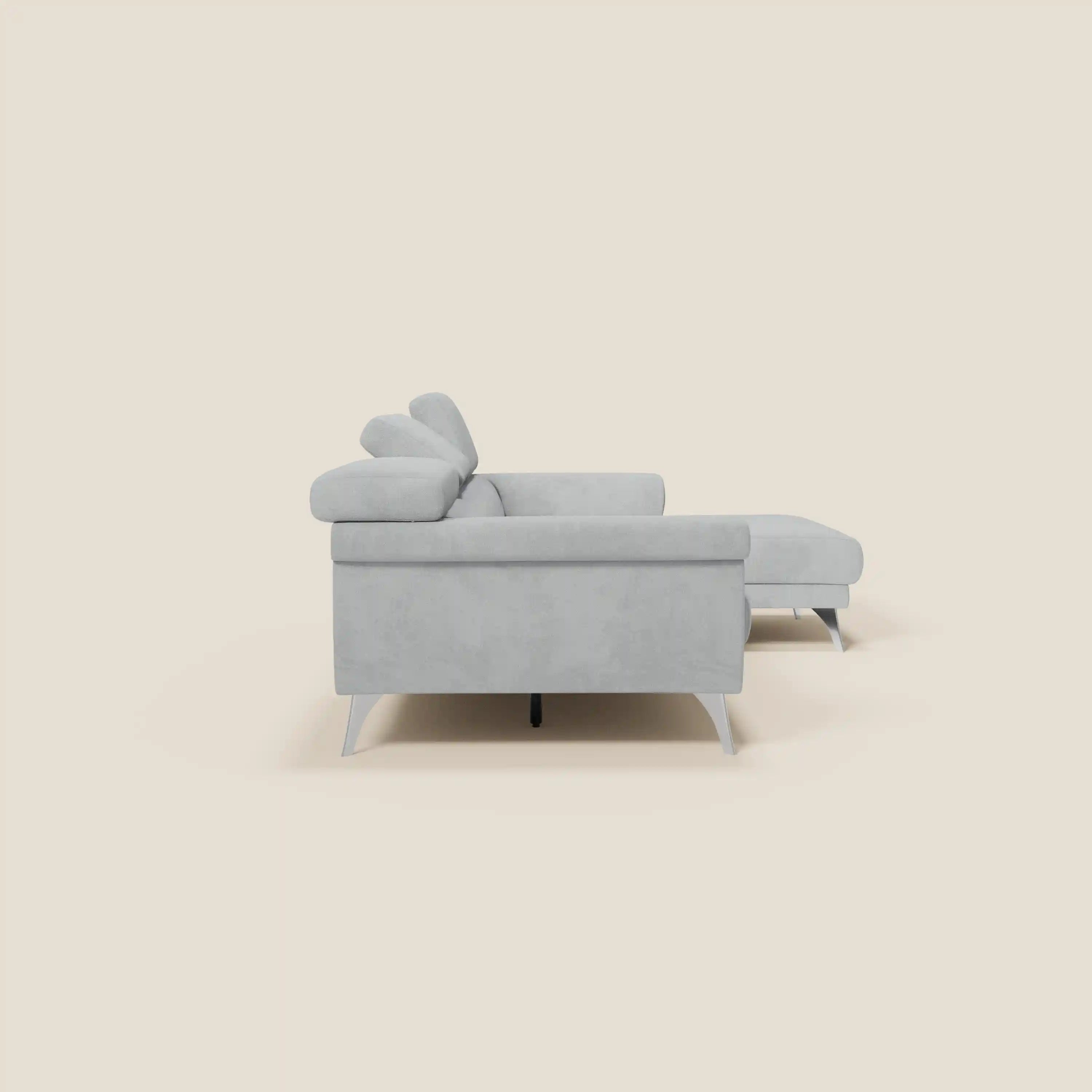 Il Raffaello Divano angolare di Divani.Store in microfibra smacchiabile T11 grigio chiaro è dotato di sedute scorrevoli, poggiatesta regolabili e si presenta lateralmente con cuscini di schienale angolari e gambe affusolate su sfondo beige.