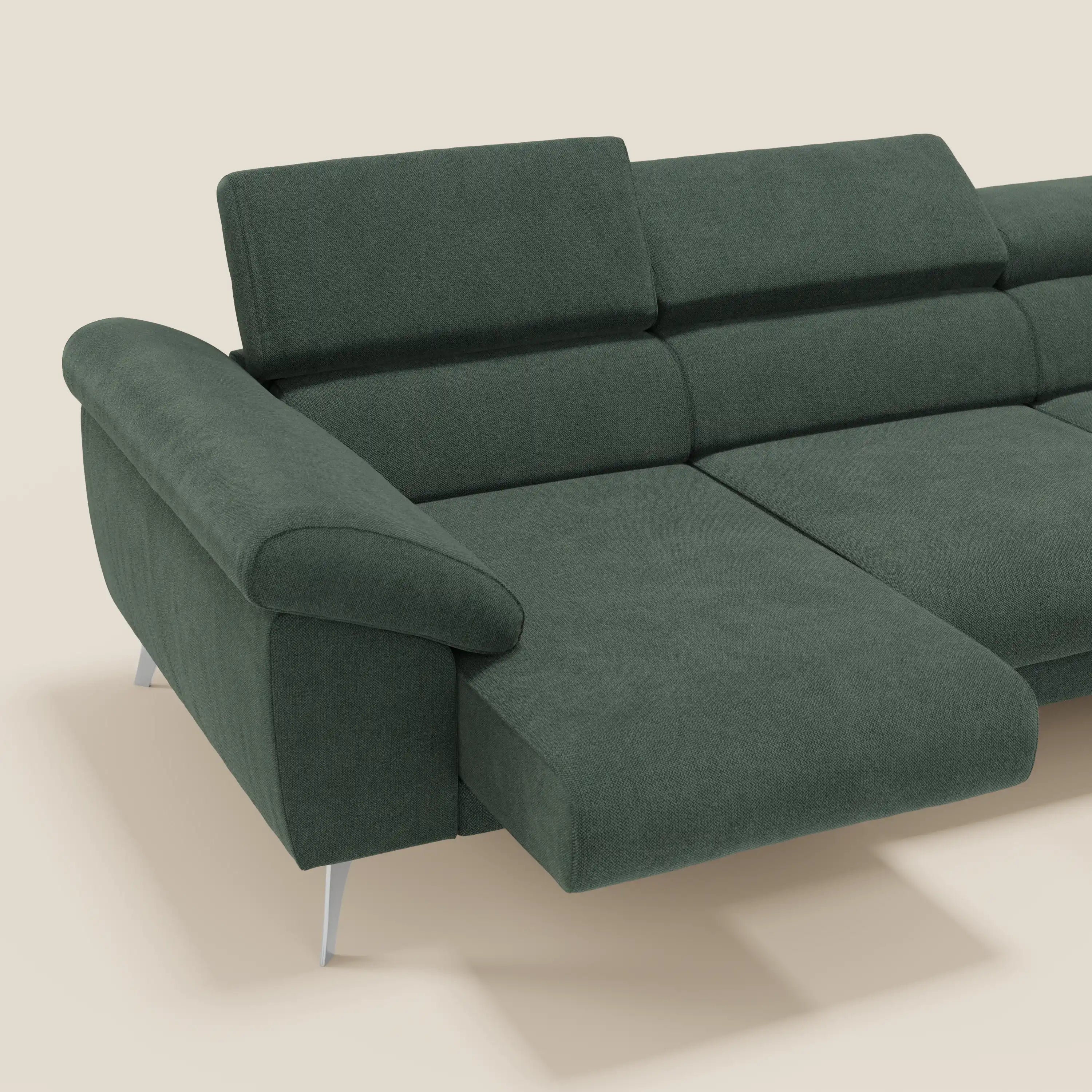 Il Donatello Divano angolare di Divani.Store, in tessuto verde T23 facile da pulire, è caratterizzato da sedute scorrevoli, braccioli contenitori e poggiatesta regolabili. Include una chaise lounge sul lato sinistro e spicca su uno sfondo beige chiaro.