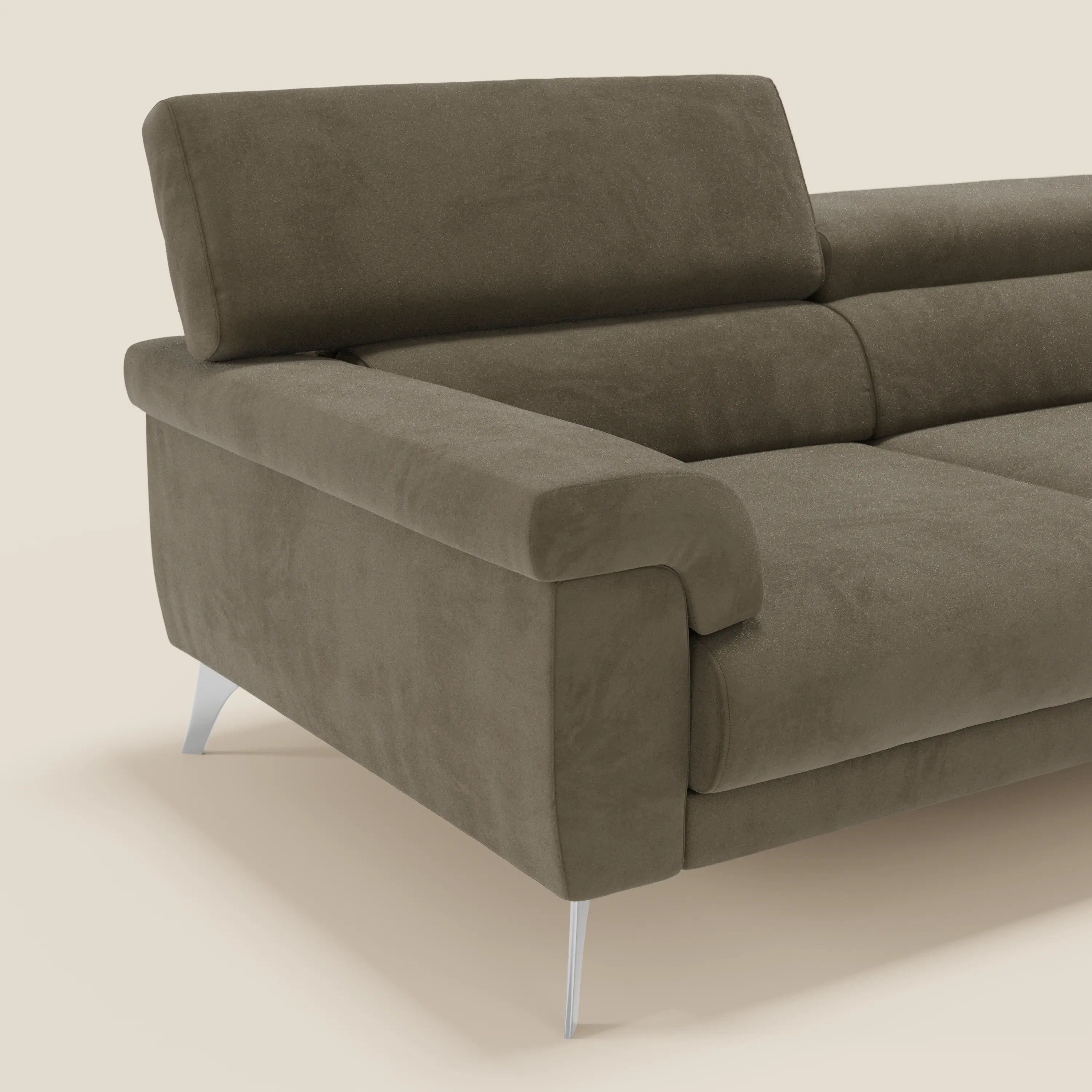 Primo piano del divano Raffaello di Divani.Store, con rivestimento in microfibra smacchiabile T11 marrone, ampi braccioli, sedute allungabili, poggiatesta reclinabili e gambe angolari in metallo color argento su sfondo beige chiaro.