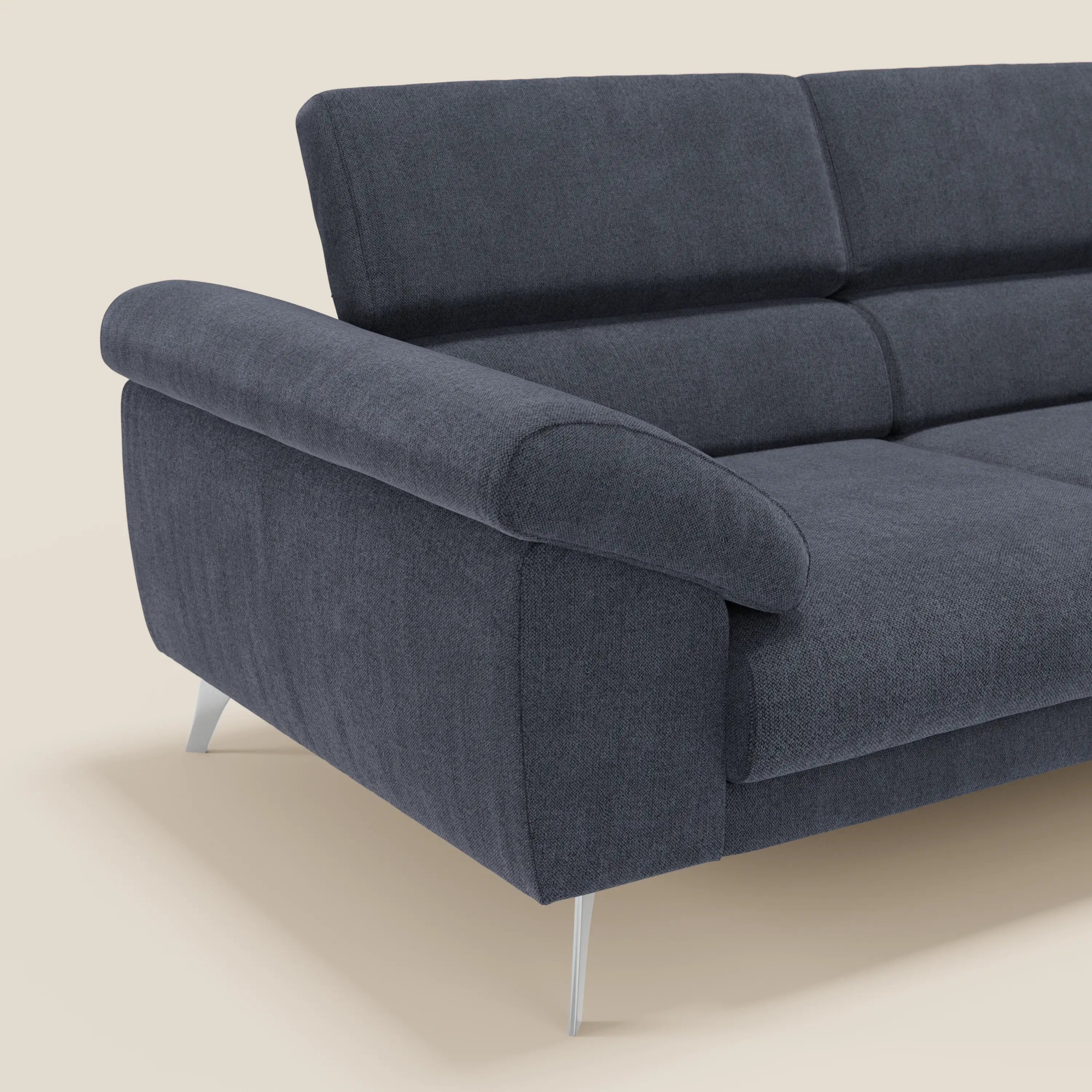 Divano moderno Donatello di Divani.Store, in smacchiabile T23 blu ardesia, con braccioli contenitore, sedute allungabili, poggiatesta reclinabili e gambe in metallo. Solo un'estremità e parte della seduta appaiono su uno sfondo beige chiaro.