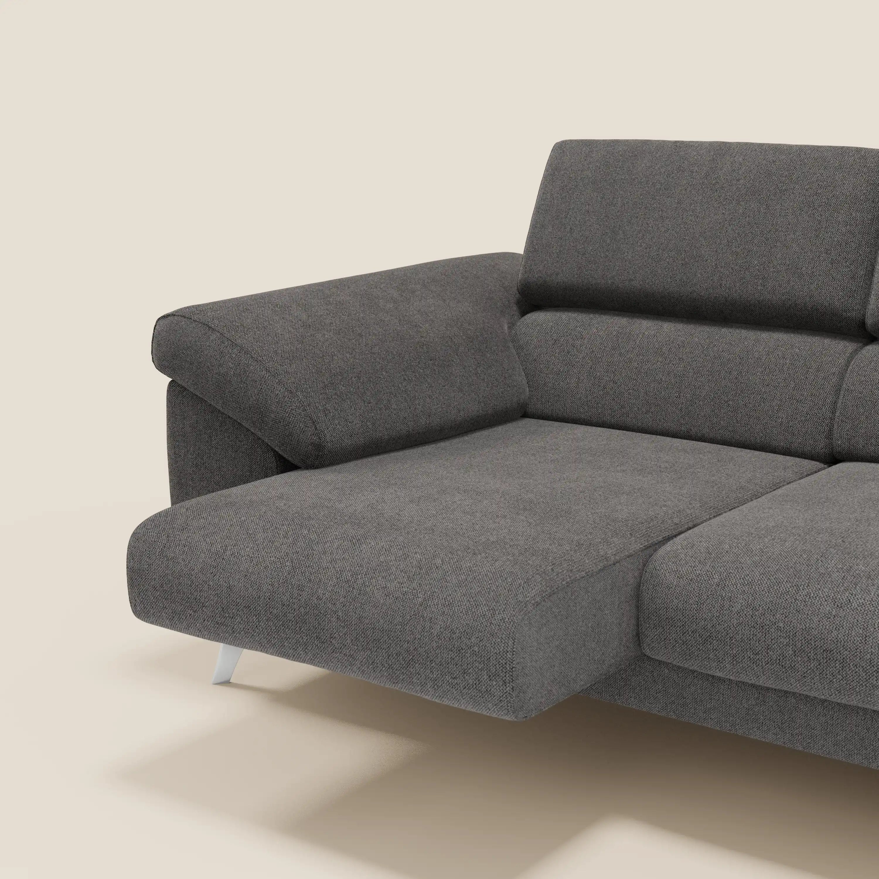 Il divano Donatello di Divani.Store in smacchiabile T23 antracite è caratterizzato da 3 sedute allungabili, braccioli contenitore, poggiatesta reclinabili e gambe corte in argento. Questo divano moderno è dotato di una chaise a sinistra e di cuscini morbidi su sfondo beige.