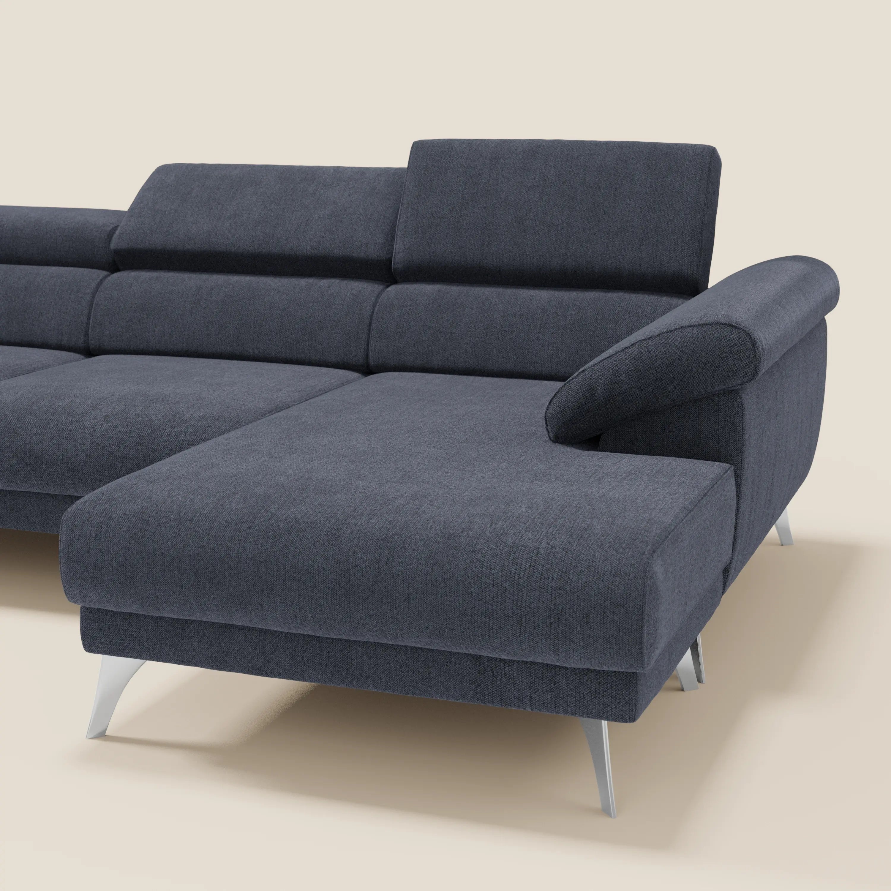 Il divano angolare Donatello di Divani.Store è caratterizzato da sedute scorrevoli, braccioli contenitori e poggiatesta regolabili in morbido tessuto di ardesia blu T23 antimacchia, su uno sfondo beige tinta unita che mette in risalto la spaziosa chaise longue.