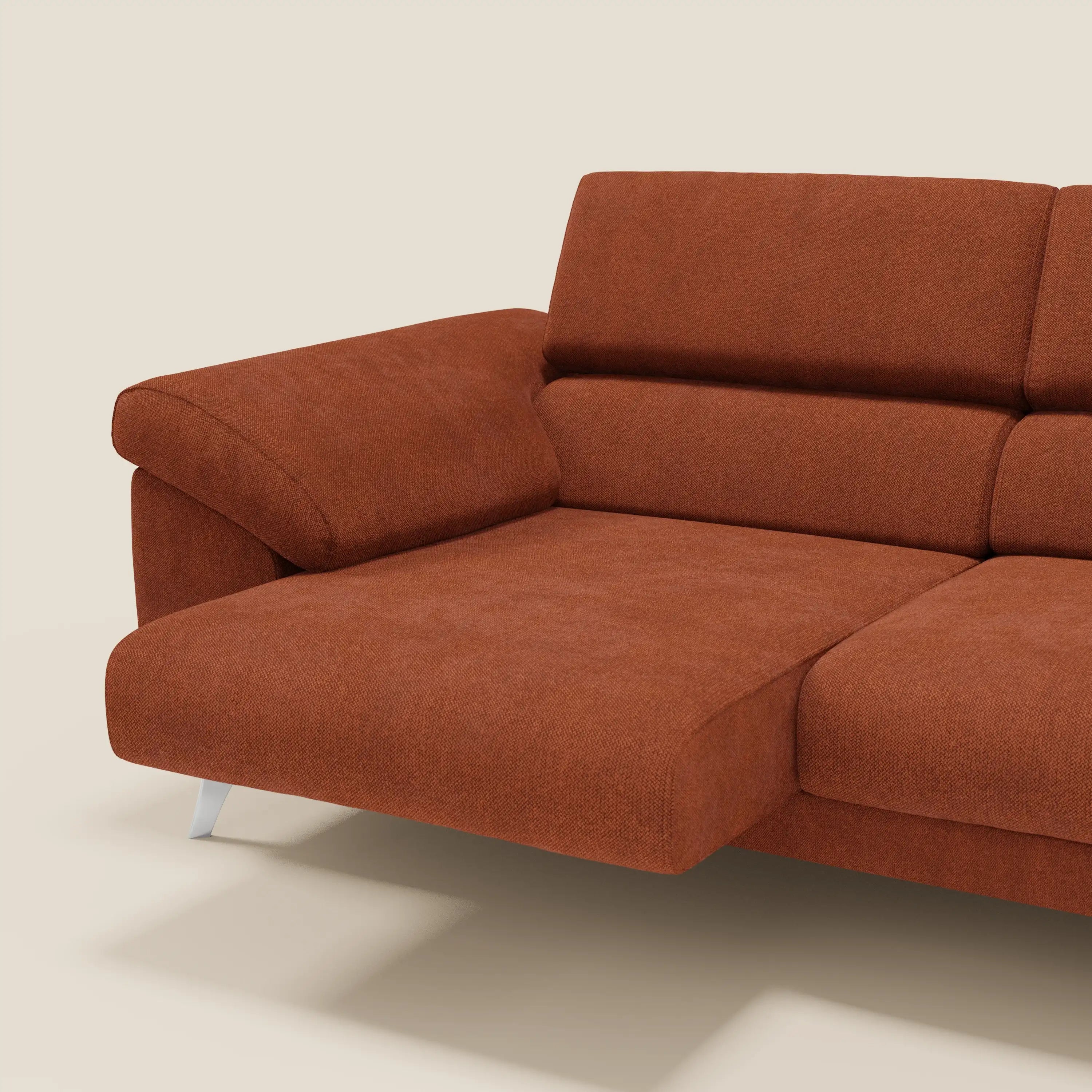 Primo piano del divano Donatello di Divani.Store in ruggine arancione T23, con sedute allungabili, braccioli contenitore, poggiatesta reclinabili e tessuto smacchiabile, su sfondo beige chiaro.