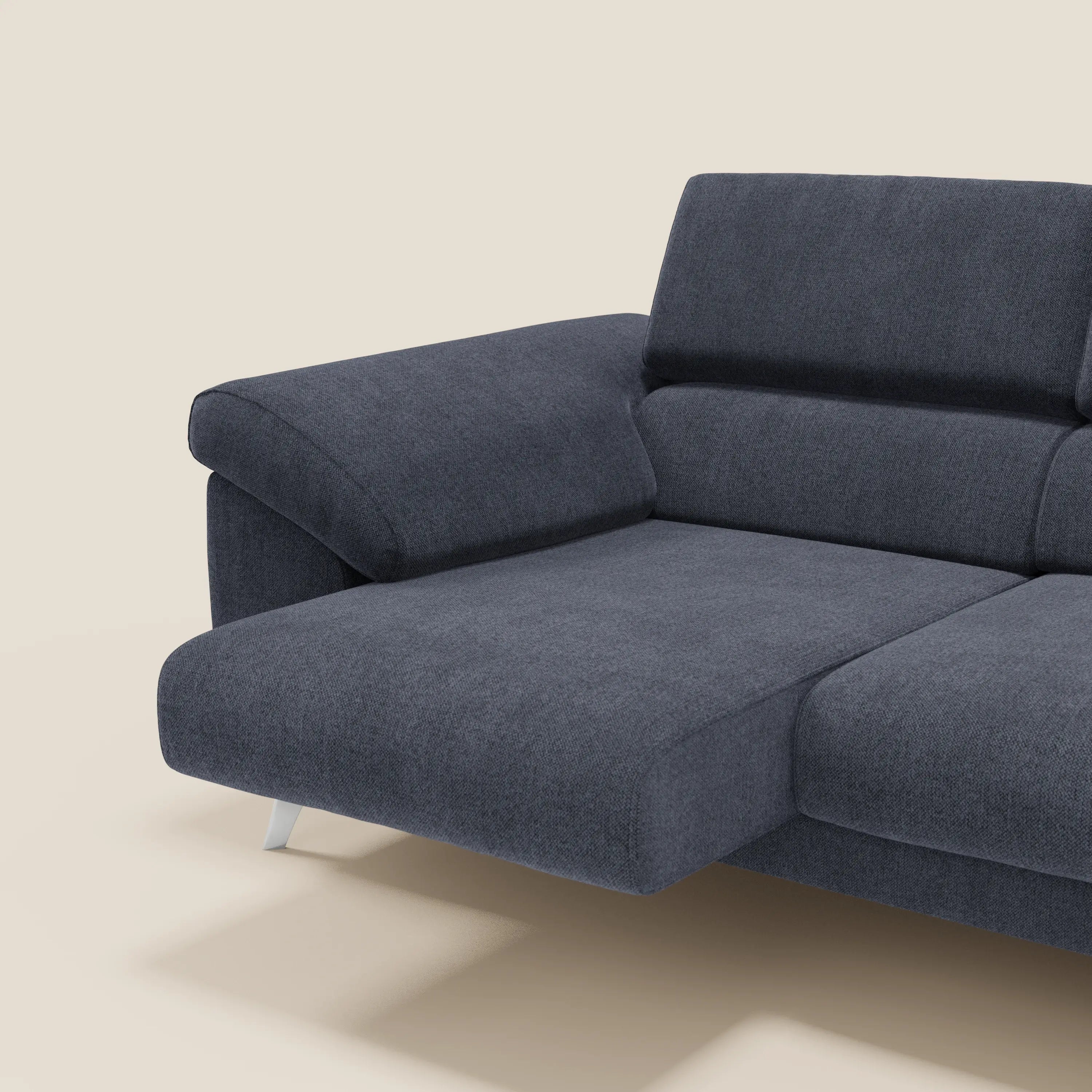 Donatello divano blu ardesia di Divani.Store con 3 sedute allungabili, braccioli contenitore e poggiatesta reclinabili in tessuto smacchiabile T23. Solo una parte del divano è visibile su sfondo beige chiaro, evidenziando il suo design moderno.