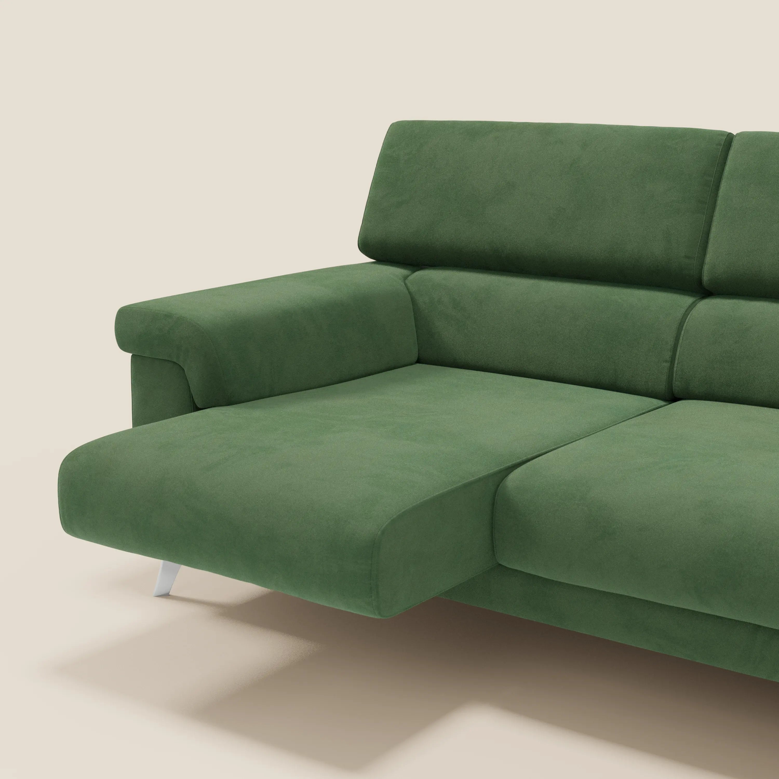 Il Raffaello di Divani.Store è un moderno divano angolare verde con sedute scorrevoli, poggiatesta regolabili e gambe corte in metallo, rivestito in microfibra smacchiabile T11 verde. Sfondo: tinta unita beige chiaro.