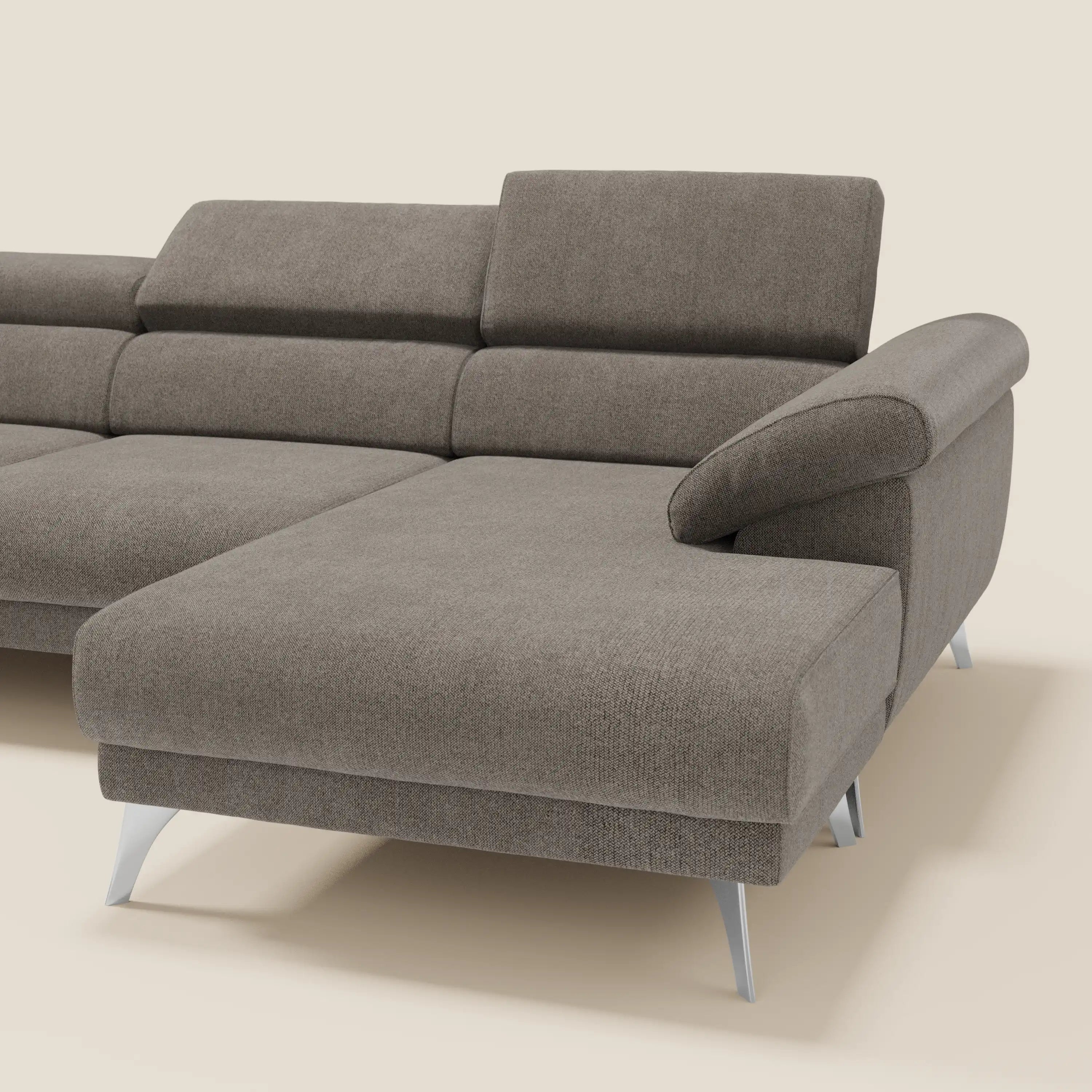 Il Donatello Divano angolare di Divani.Store è caratterizzato da sedute scorrevoli, braccioli contenitore e poggiatesta in morbido tessuto talpa T23 antimacchia, per offrire un comfort versatile e un'eleganza moderna su un semplice sfondo beige.