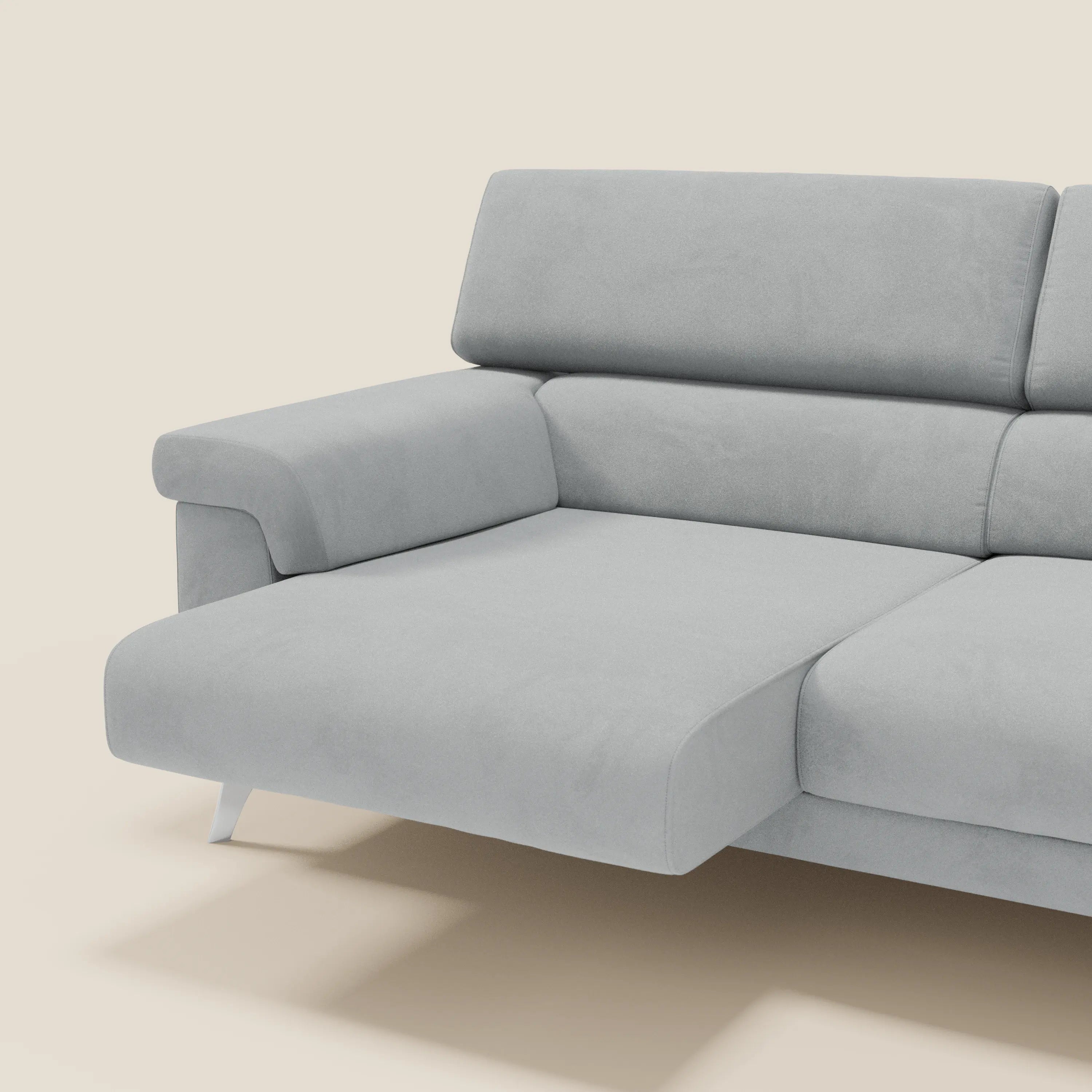 Il divano Raffaello con sedute allungabili e poggiatesta reclinabili in microfibra smacchiabile T11 grigio chiaro di Divani.Store è presentato con ampi braccioli, seduta a chaise e piedini angolari in metallo su sfondo beige.