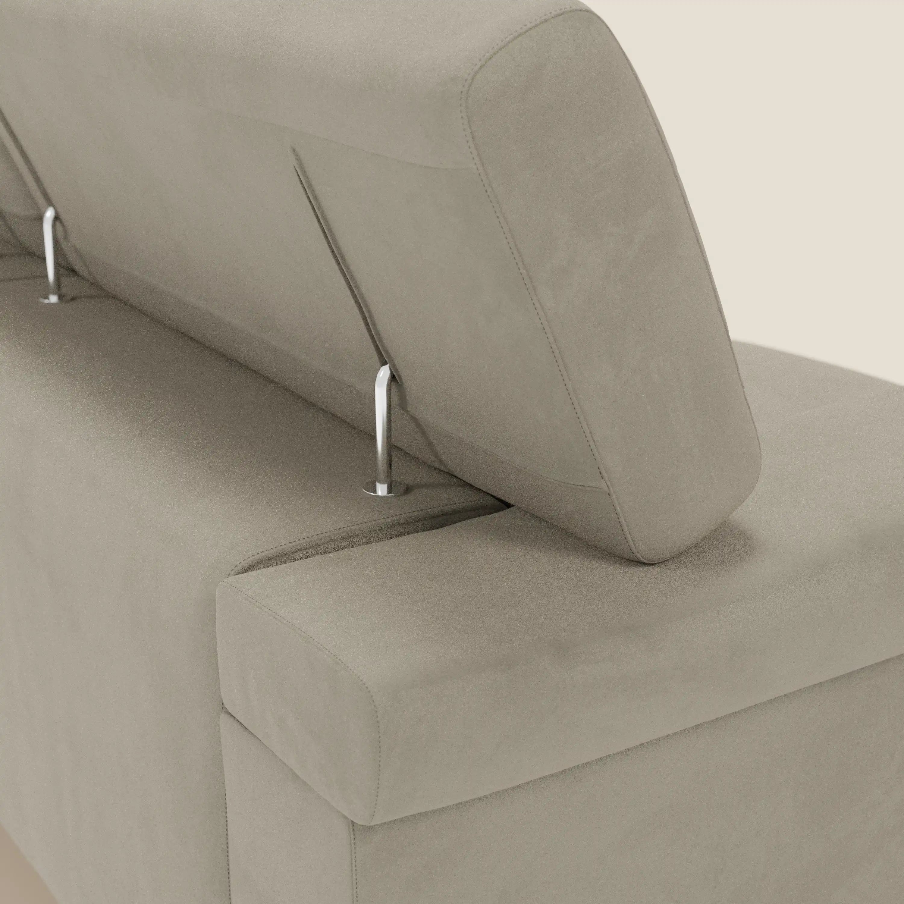 Un primo piano del divano Raffaello di Divani.Store mostra il suo schienale in microfibra tortora T11 con poggiatesta regolabile su aste metalliche, che offre un comfort avanzato e una sensazione di morbidezza su un semplice sfondo bianco sporco.