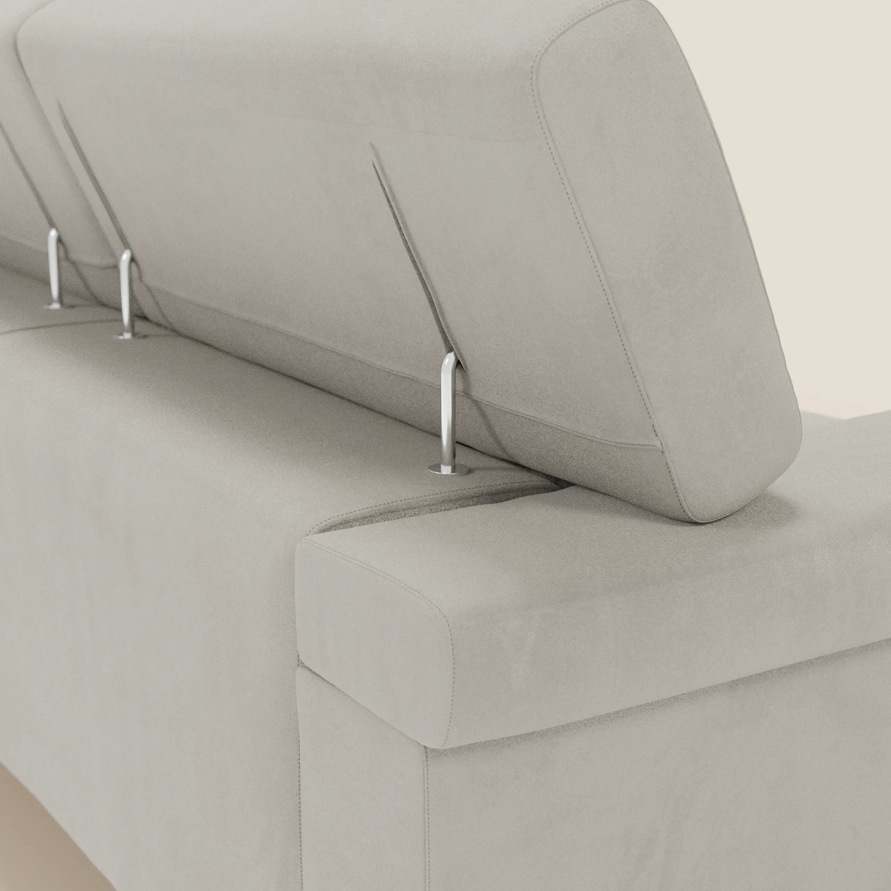 Un primo piano del divano angolare Raffaello di Divani.Store, in smacchiabile microfibra panna T11, mostra i suoi seduti scorrevoli e poggiatesta regolabili con eleganti aste metalliche, su uno sfondo tinta unita crema per un look moderno.