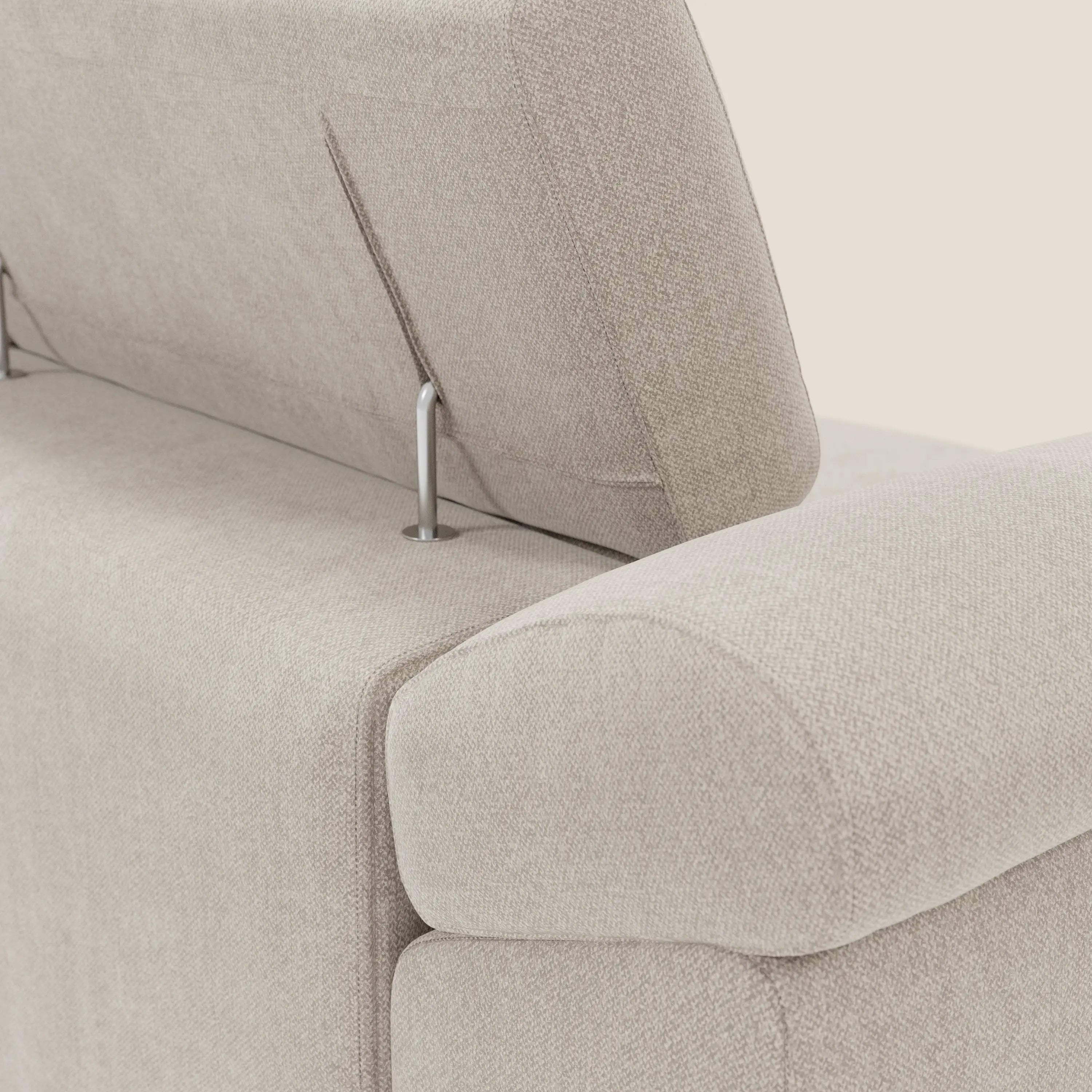 Primo piano del divano Donatello di Divani.Store in tessuto smacchiabile T23 panna, caratterizzato da 3 sedute allungabili, braccioli contenitore e poggiatesta reclinabili su sottili gambe in metallo, che ne evidenziano il contemporaneo comfort regolabile.