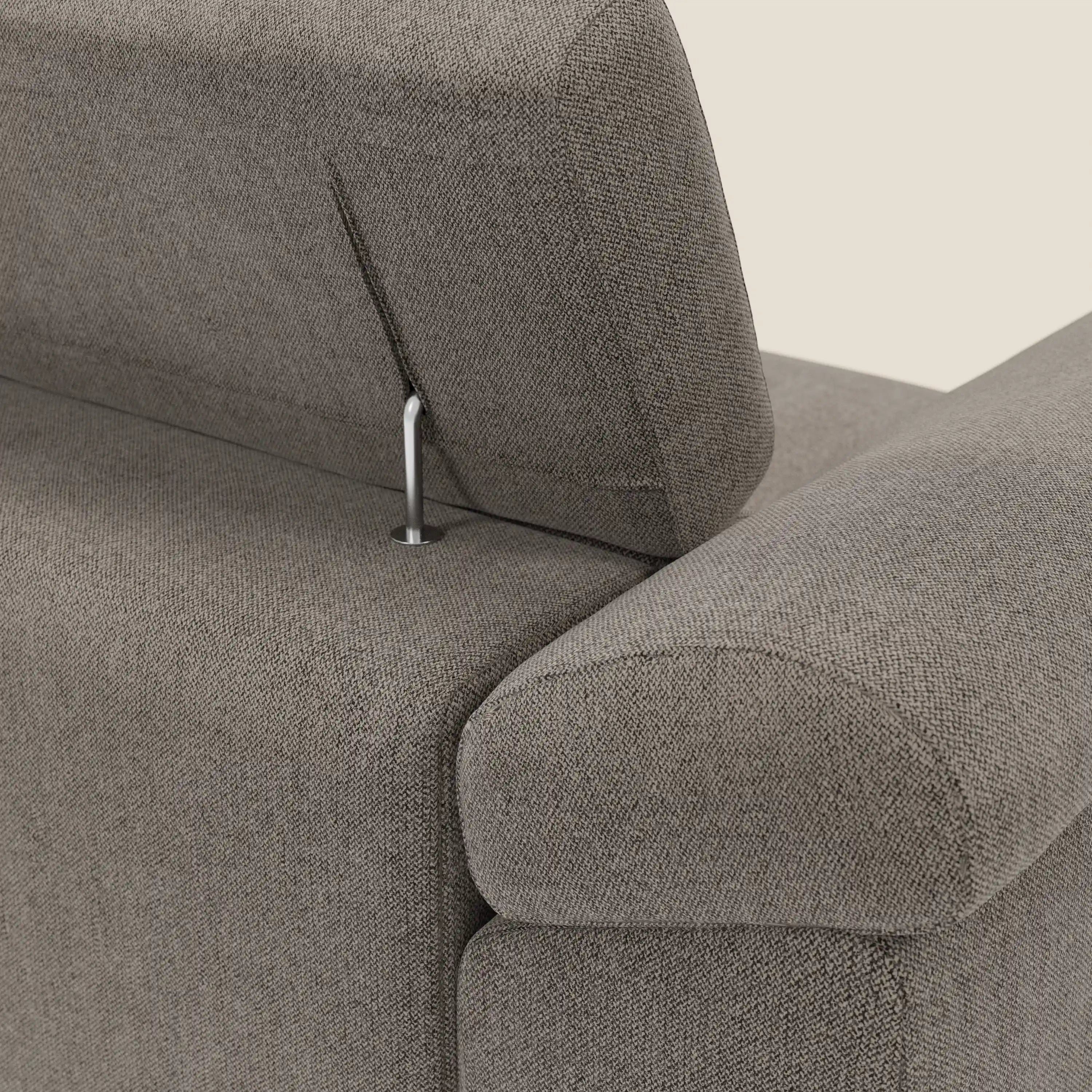 Primo piano del Divano angolare Donatello di Divani.Store in morbido tessuto talpa T23 antimacchia, con sedili scorrevoli, braccioli portaoggetti e poggiatesta regolabile. Il rivestimento è strutturato e confortevole. Sfondo beige a tinta unita.