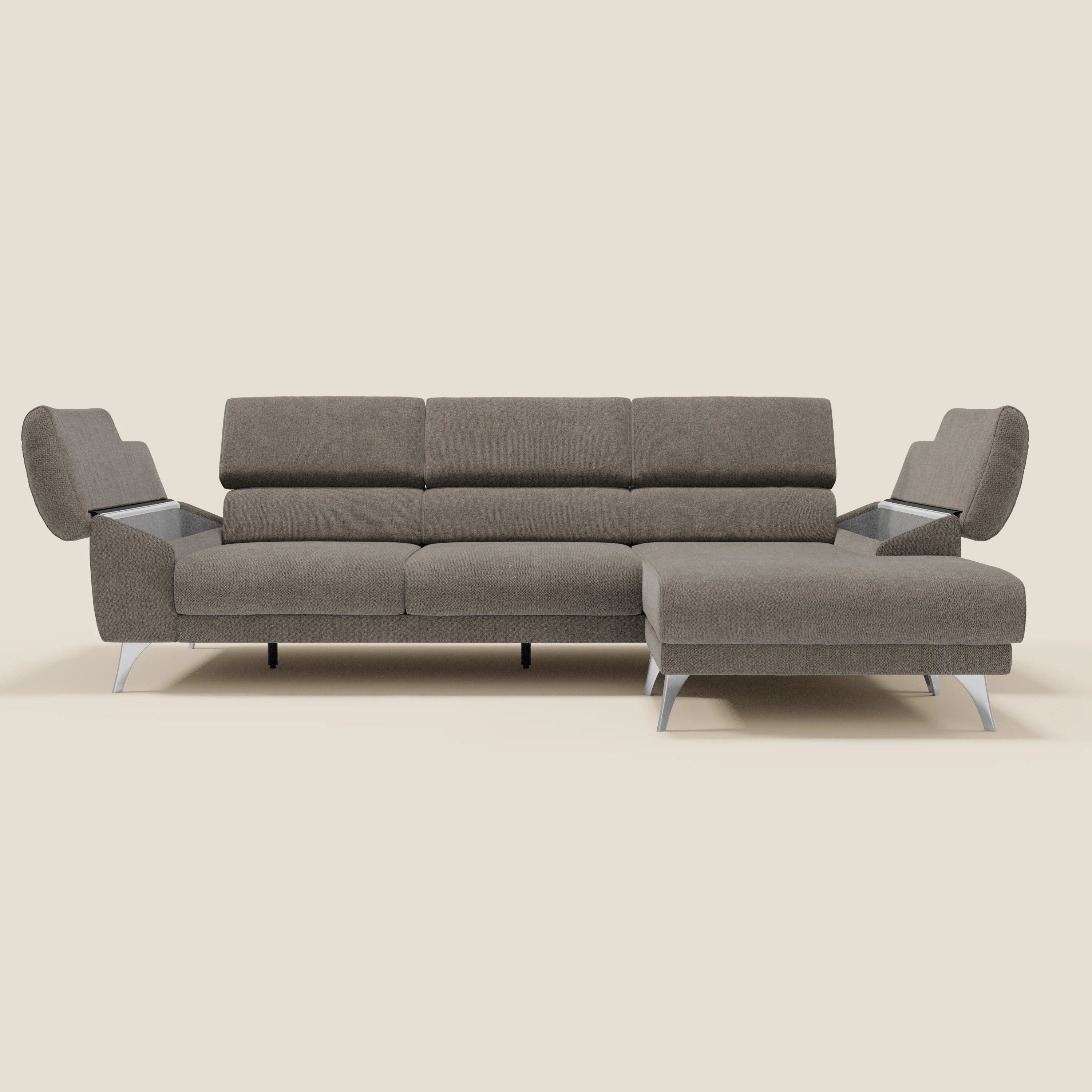 Il Donatello Divano angolare di Divani.Store è dotato di 5 posti, sedute scorrevoli, braccioli portaoggetti, poggiatesta regolabili e rivestimento in morbido tessuto antimacchia T23 taupe. Presentato con chaise longue a destra e gambe angolari in metallo su sfondo beige.