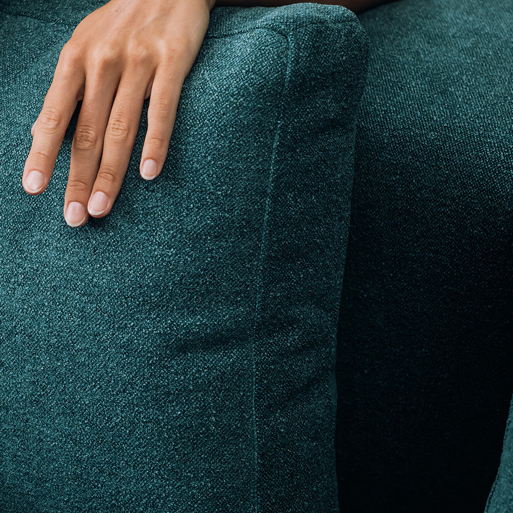 Un primo piano mostra una mano sinistra appoggiata sul divano T07 Dalt Tessuto Boucle basso morbido ed impermeabile di Divani.Store, con unghie ben curate e un'illuminazione che mette in risalto la trama del tessuto e i toni naturali della pelle.