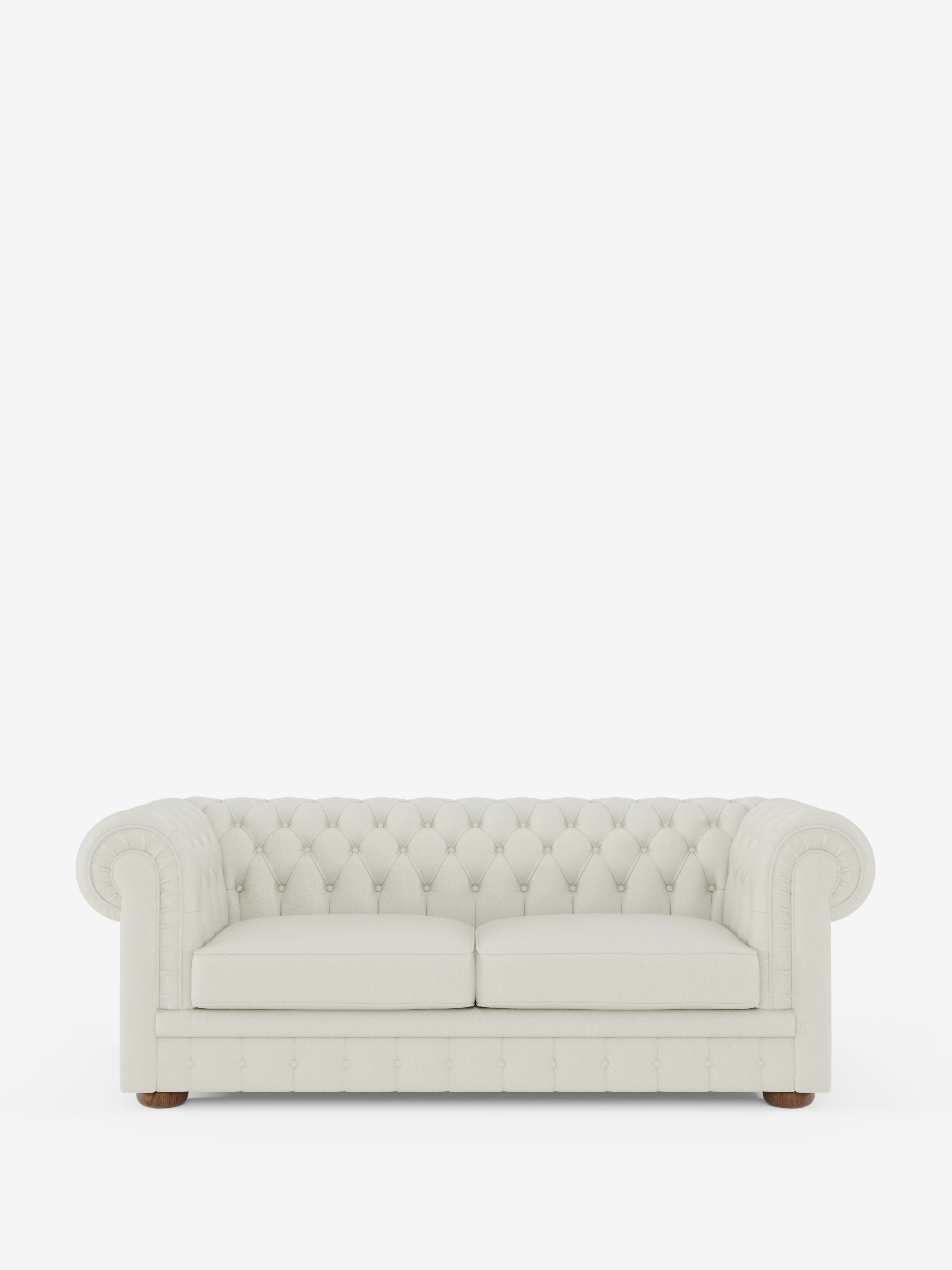 Un divano Chesterfield color crema in pelle trapuntata – Divano Chesterfield in vera pelle spessorata a 2 e 3 posti di Divani.Store, caratterizzato da braccioli arrotondati e due cuscini di seduta, poggia su piccoli piedini in legno su uno sfondo bianco a tinta unita, mettendo in risalto la raffinata maestria artigianale di un divano italiano fatto a mano.