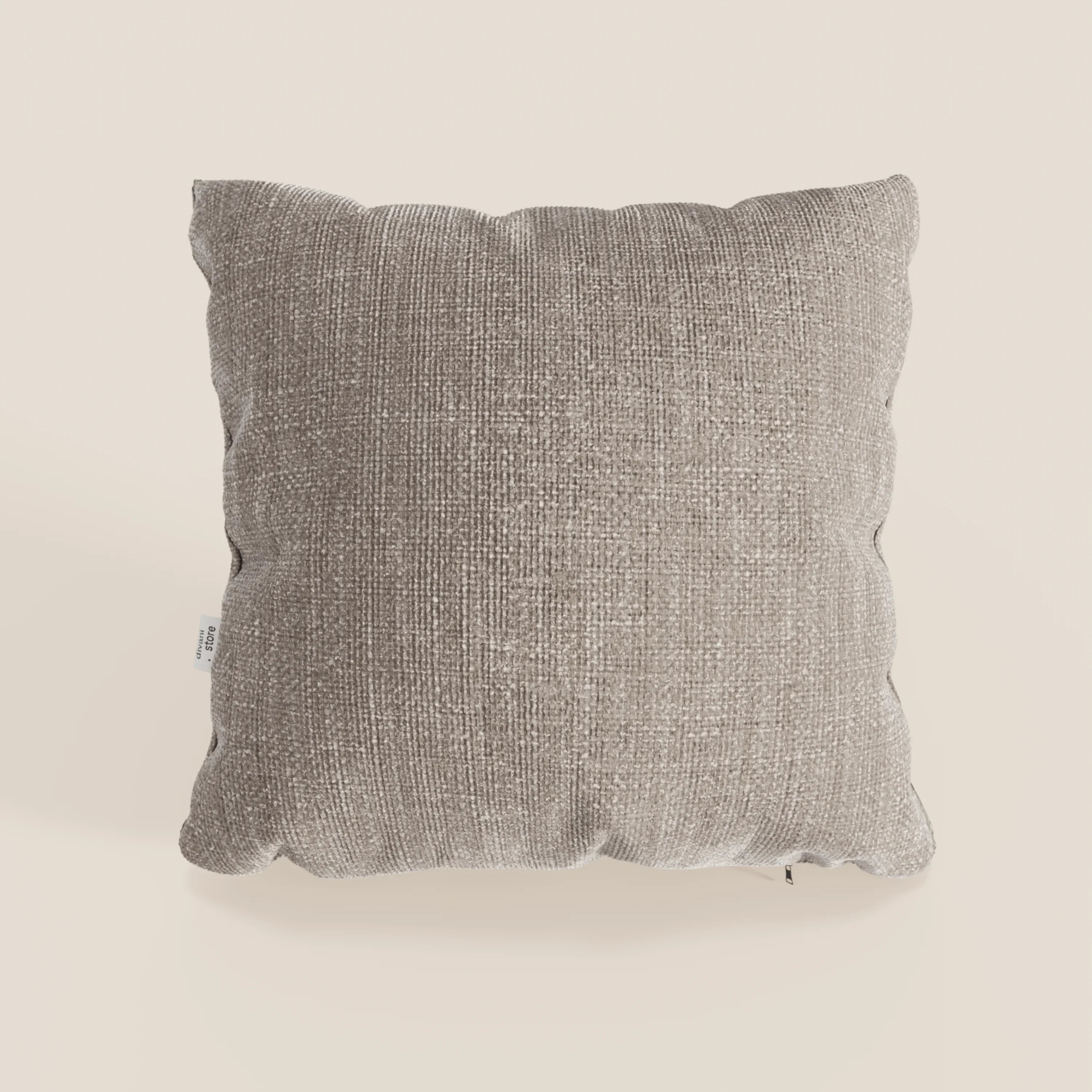 Il cuscino Lyon di Divani.Store, presentato nel colore T06 tortora, ha forma quadrata, tessuto impermeabile testurizzato, angoli arrotondati, aspetto morbido e imbottito e una piccola etichetta sul lato sinistro su uno sfondo beige chiaro.