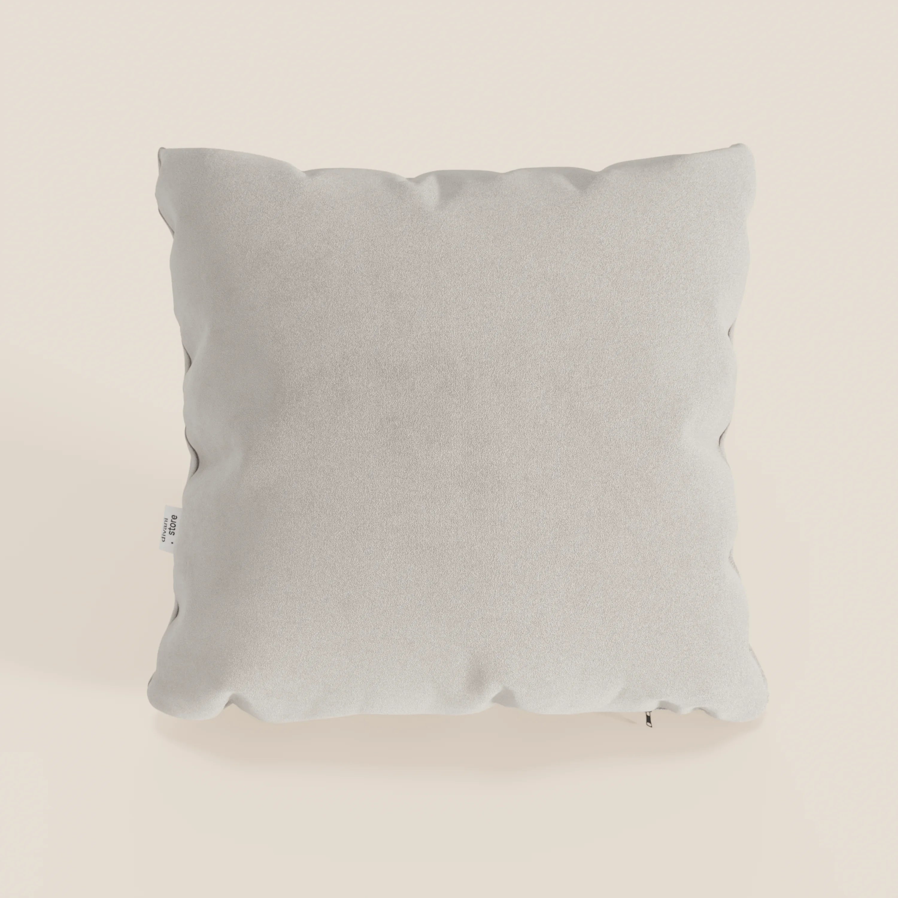 Il cuscino Jazz di Divani.Store, in T11 panna smacchiabile microfibra tecnica, è quadrato e di colore grigio chiaro, con una consistenza morbida e liscia. Presenta una piccola etichetta in tessuto bianco sulla cucitura sinistra e appare soffice su uno sfondo bianco sporco.