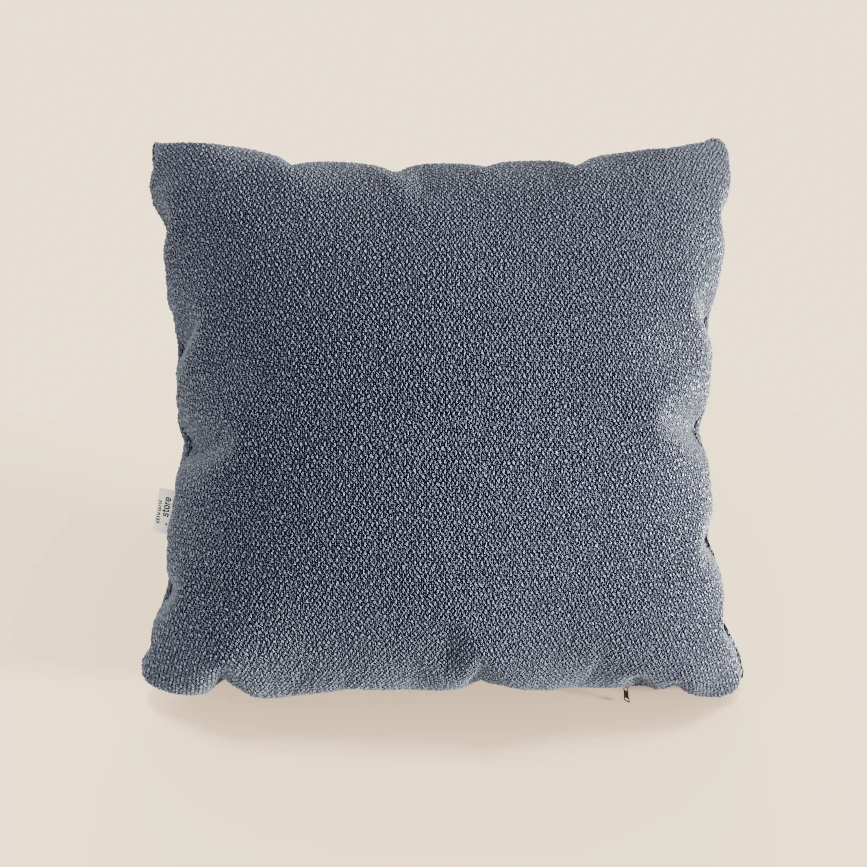 Il cuscino Lambada di Divani.Store, presentato in un tessuto strutturato blu scuro, ha una forma quadrata con un bordo morbido e leggermente irregolare e una targhetta bianca a vista. Realizzato in tessuto smacchiabile e impermeabile tipo cotone T33.