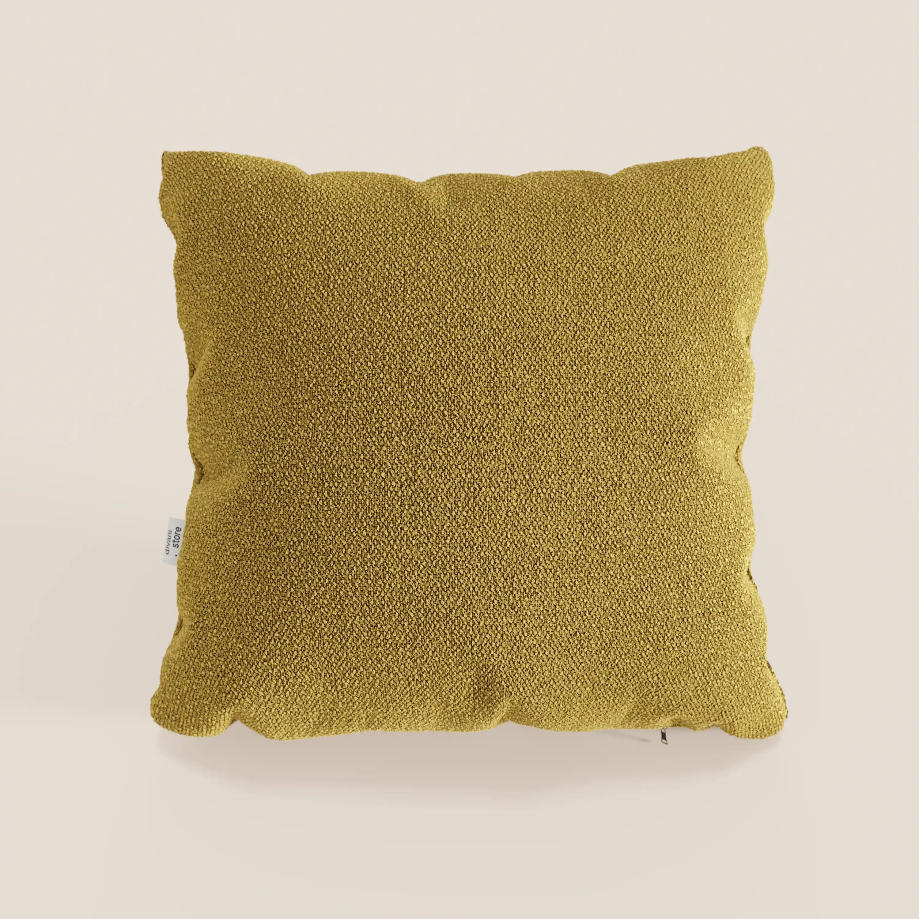 Un cuscino Lambada quadrato giallo senape di Divani.Store si trova al centro di uno sfondo beige chiaro. Realizzato in fresco tessuto simil-cotone T33, antimacchia e impermeabile, presenta una consistenza morbida e un'etichetta in tessuto sul bordo sinistro.