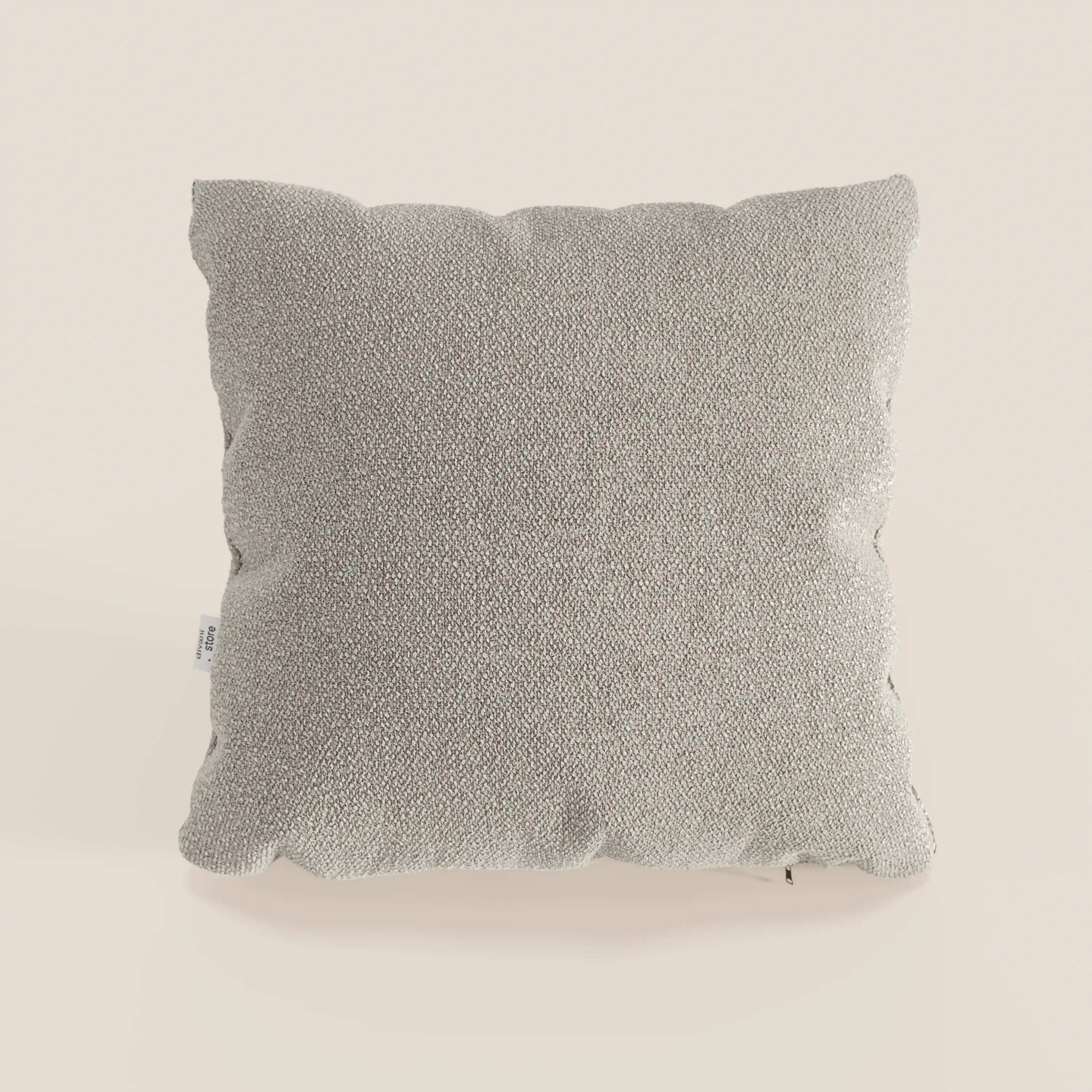 Cuscino Lambada quadrato grigio chiaro di Divani.Store in tessuto T33 lavabile e impermeabile, simile al cotone, con una texture sottile, su uno sfondo bianco sporco. Una piccola etichetta bianca compare sul bordo sinistro del cuscino.