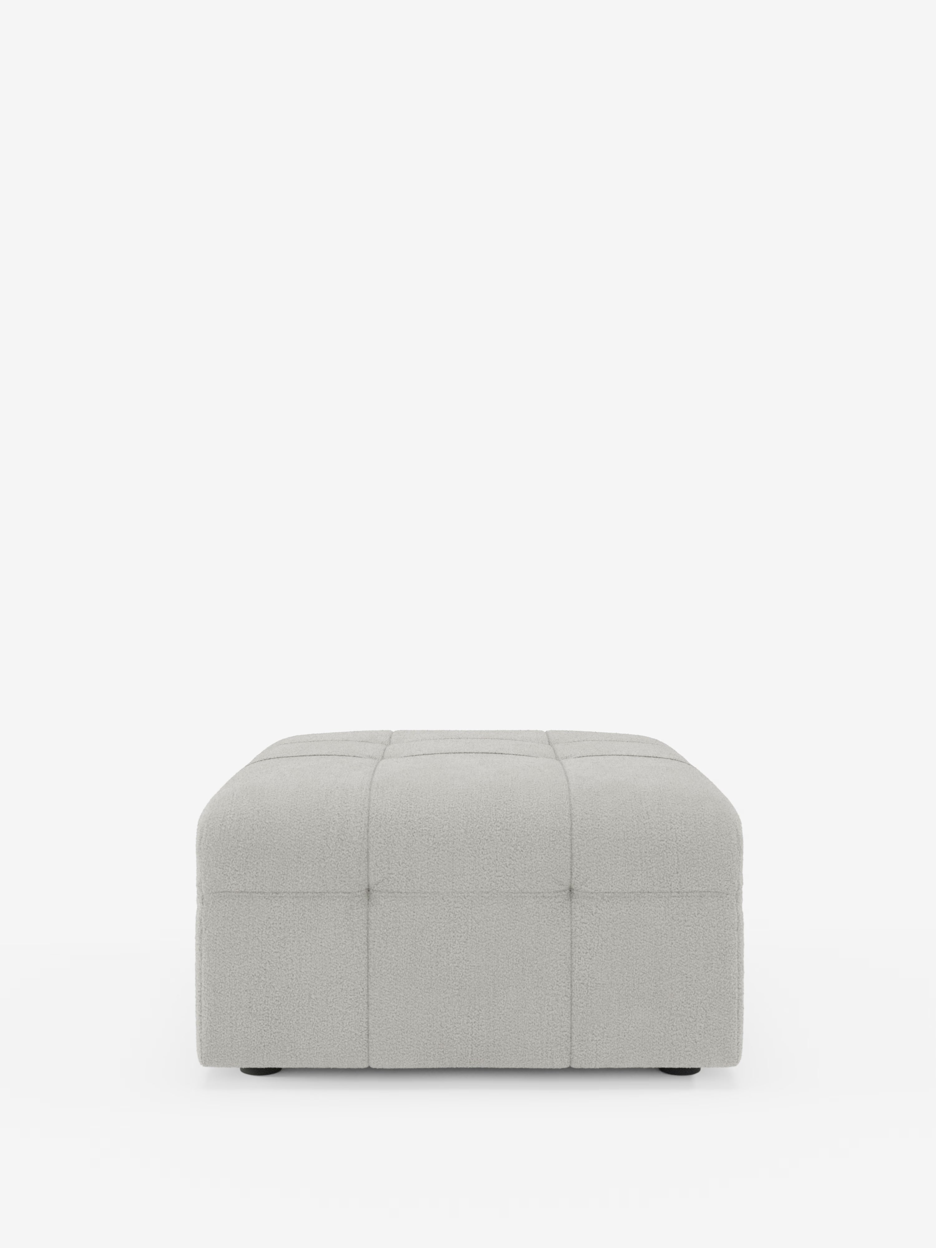 Un pouf quadrato Mosaic, di colore grigio chiaro, in bouclé di Divani.Store, spicca su uno sfondo bianco. Con dimensioni di 96x77 cm, la sua superficie è elegantemente rivestita in tessuto bouclé T21 antimacchia, con sottili cuciture orizzontali e verticali che formano un raffinato motivo a griglia capitonné che ricorda le tessere di un mosaico sulla parte superiore e sui lati. Realizzato in Italia, il pouf poggia su piedini neri corti, discretamente nascosti sotto la base.