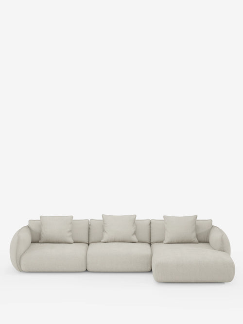 Il divano angolare con penisola componibile Nimbus in morbido tessuto effetto cotone smacchiabile T33 di Divani.Store è un divano componibile moderno, di colore beige chiaro, con tre posti e una chaise longue sul lato destro. Presenta braccioli arrotondati, morbidi cuscini e tre cuscini quadrati coordinati per lo schienale. Il design elegante di questo divano angolare risalta su uno sfondo bianco a tinta unita.