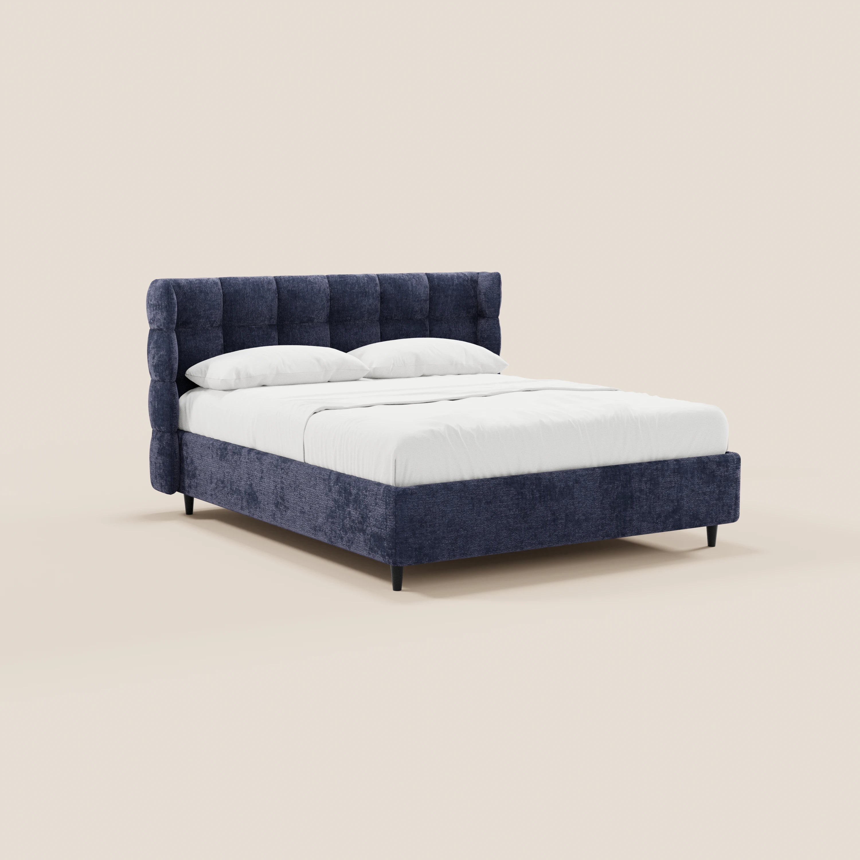 Il letto imbottito RAGNAR di Letti.store presenta una testiera capitonné avvolgente in elegante tessuto blu certificato Oeko-Tex®, dotata di vano contenitore. Il letto è rifinito con biancheria bianca e due cuscini, su uno sfondo beige chiaro.