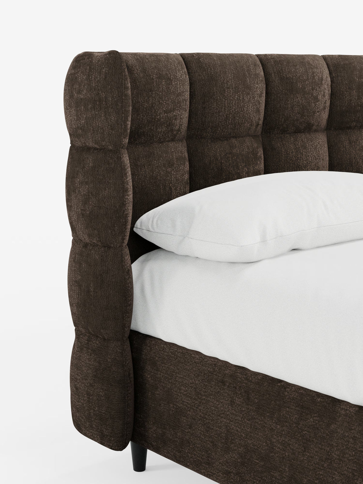 Primo piano del letto imbottito RAGNAR con contenitore e testiera capitonné avvolgente di Letti.store, realizzato con un elegante rivestimento marrone scuro certificato Oeko-Tex®. La testiera capitonné e la base presentano bordi arrotondati e imbottiti, poggianti su gambe corte e scure. Un cuscino bianco riposa su un materasso bianco abbinato, su uno sfondo bianco a tinta unita.