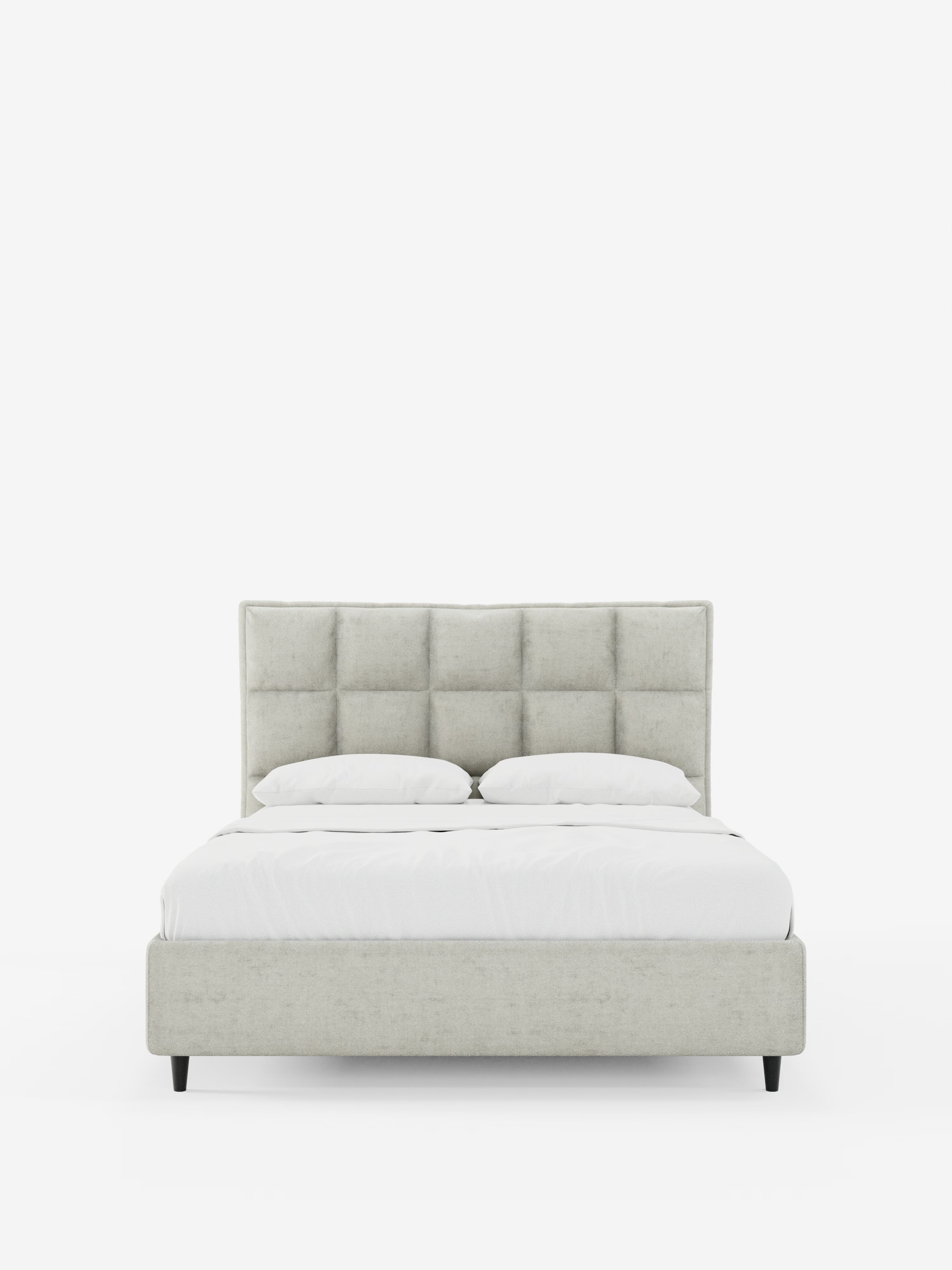 AURO di Letti.store è un moderno letto matrimoniale caratterizzato da un’alta testiera capitonné trapuntata, rivestita in ciniglia grigio chiaro certificata Oeko-Tex®. Questo elegante letto imbottito, dotato di un pratico vano contenitore, unisce stile e comfort ed è qui presentato con un lenzuolo bianco candido e due cuscini bianchi. Sostenuto da corte gambe nere e incorniciato da uno sfondo bianco a tinta unita, il design pulito del letto risalta magnificamente.