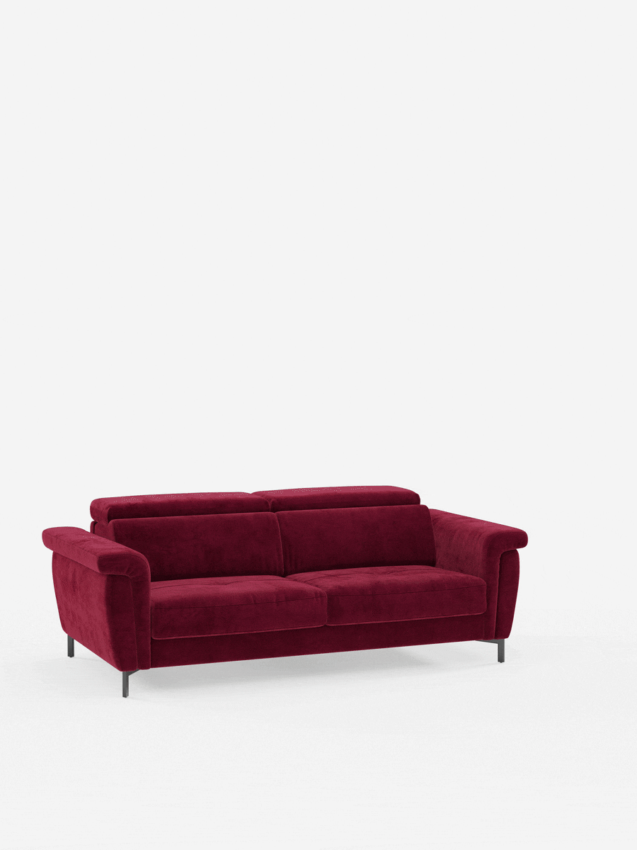 Un divano letto di design contemporaneo della linea Capri di Divani.Store, caratterizzato da gambe alte e poggiatesta regolabili, rivestito in raffinato tessuto T30 effetto velluto resistente alle macchie, spicca su uno sfondo bianco a tinta unita: il rivestimento rosso intenso e la silhouette moderna ne esaltano il comfort avvolgente e lo stile sofisticato.