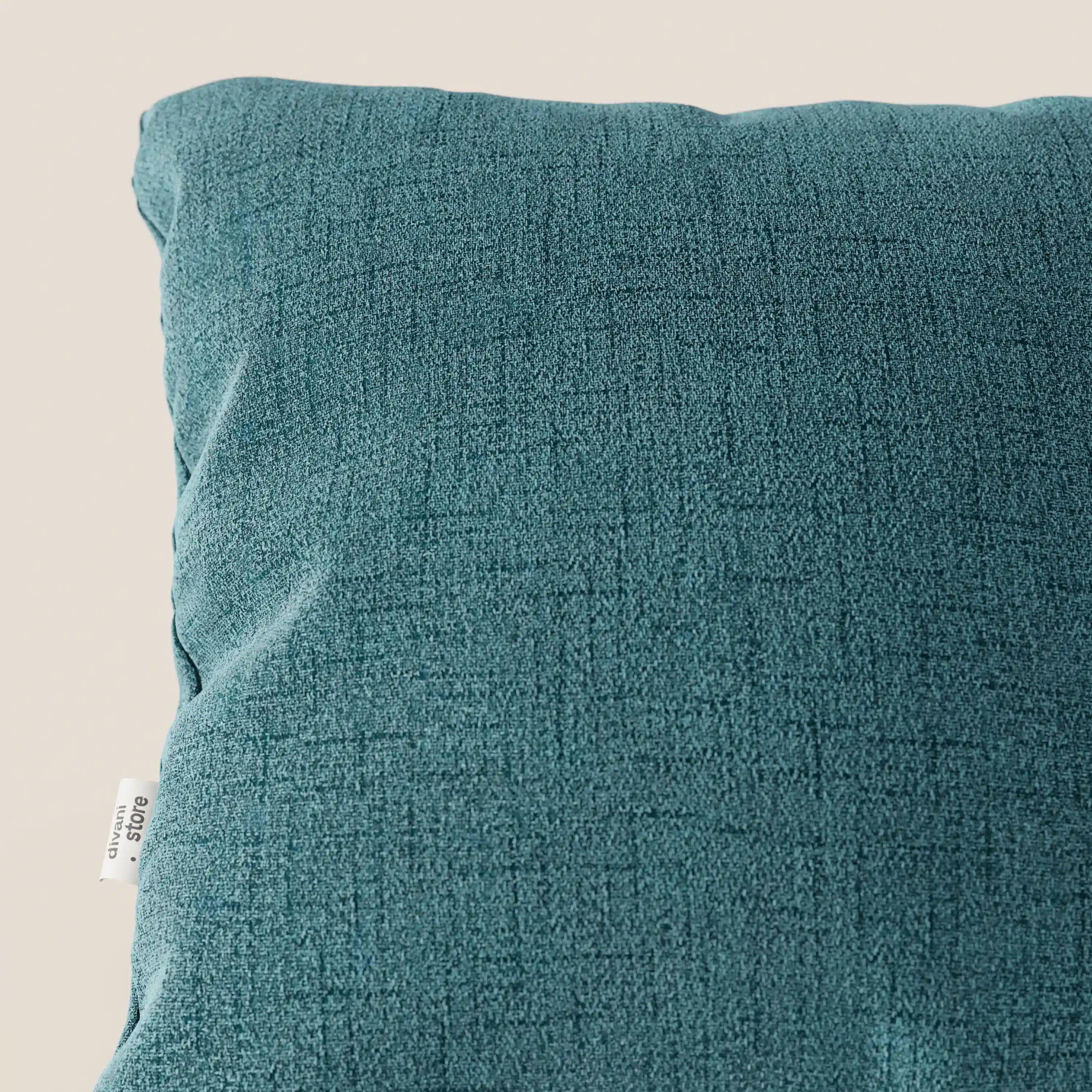 Primo piano dei cuscini Felis di Divani.Store in azzurro T03, realizzati in morbido tessuto impermeabile con una sottile trama a griglia. L'etichetta "100% cotone" compare sulla sinistra, su uno sfondo neutro e chiaro.