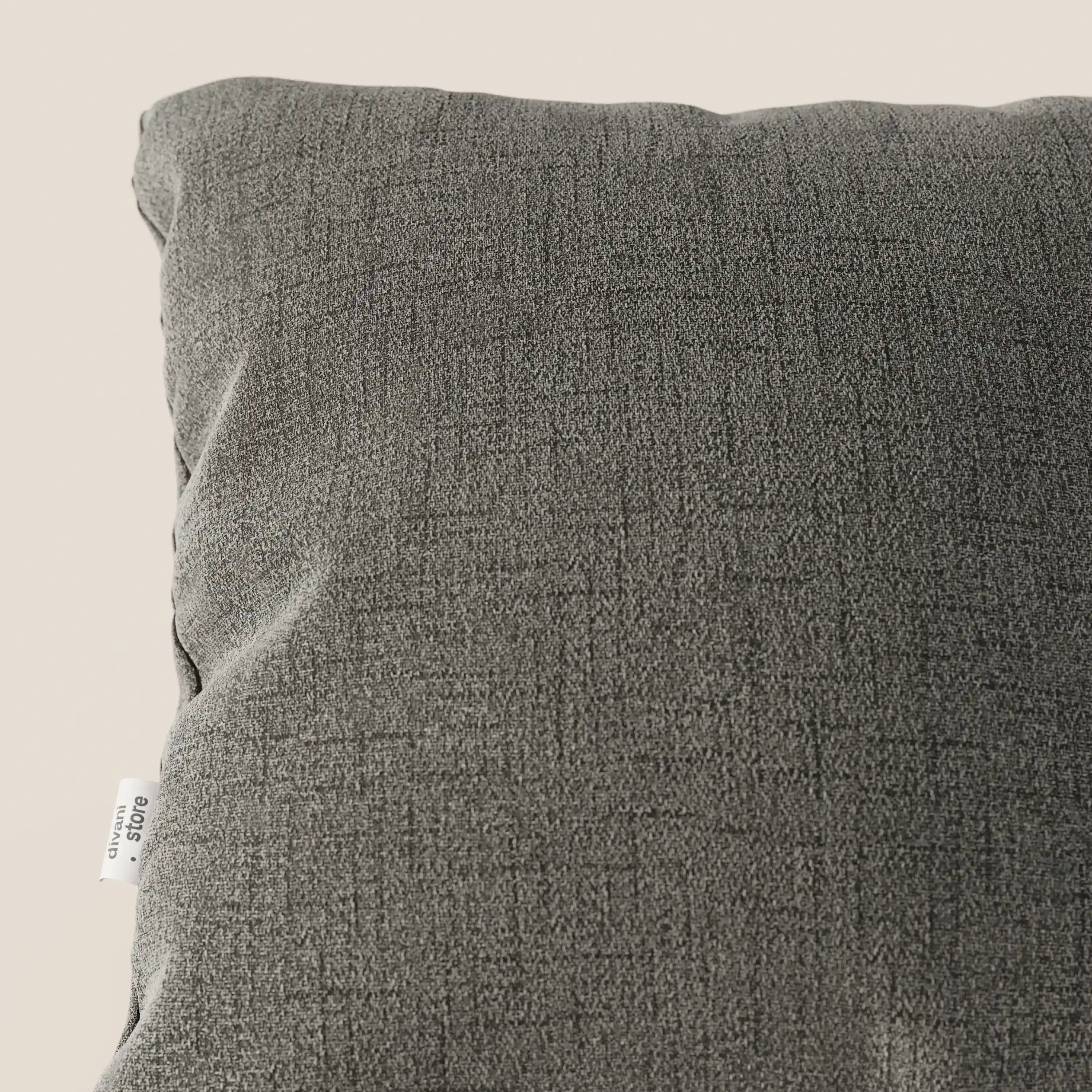 Primo piano del cuscino Felis 45x45 cm di Divani.Store in morbido tessuto impermeabile T03 talpa, con una sottile trama intrecciata e una piccola etichetta bianca, su uno sfondo beige chiaro.