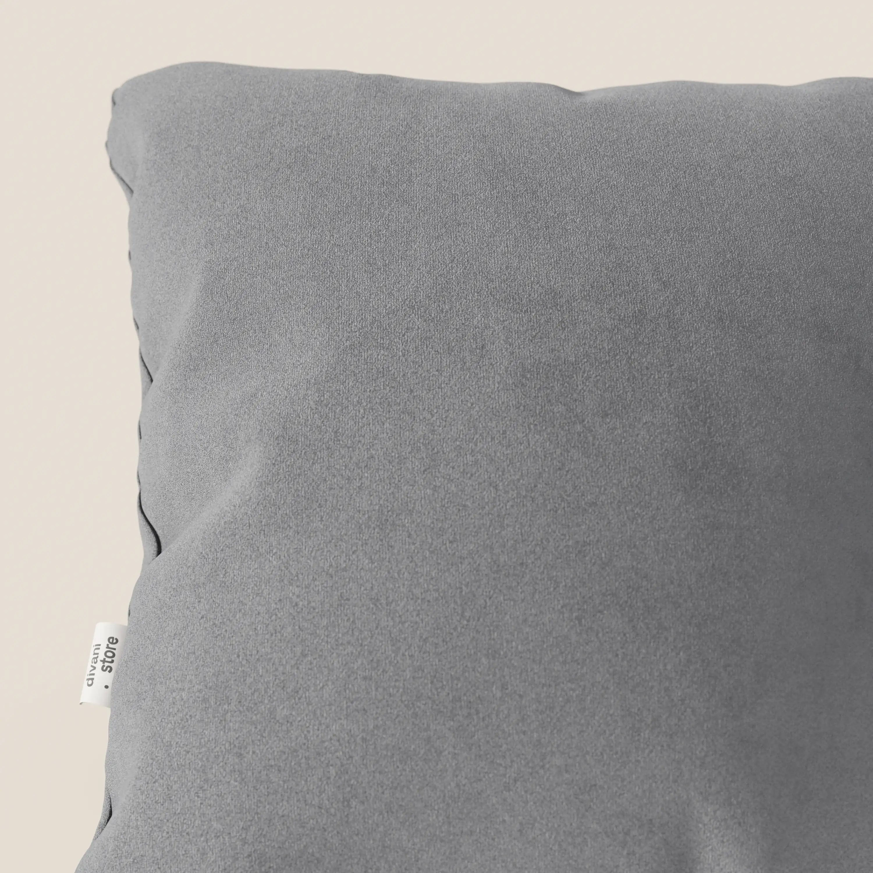 Primo piano del cuscino Jazz di Divani.Store in T11 grigio, realizzato in microfibra tecnica antimacchia. Il cuscino, di forma quadrata e morbida, presenta una texture liscia con leggere pieghe e una piccola etichetta bianca sulla cucitura sinistra su uno sfondo beige.