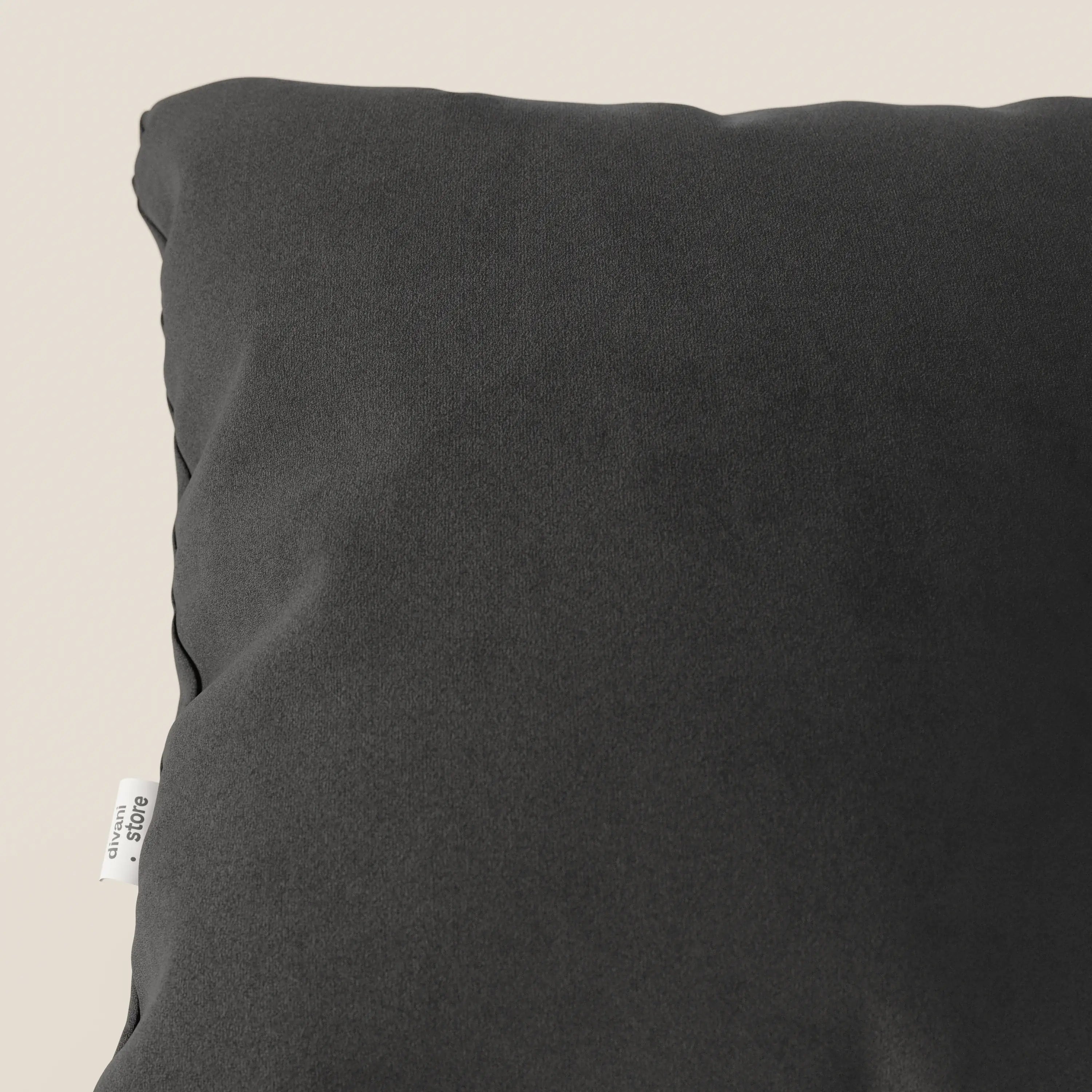 Un primo piano del cuscino Divani.Store Jazz in microfibra T11 nero mostra il suo tessuto grigio scuro, resistente alle macchie, e un'etichetta bianca sulla cucitura laterale su uno sfondo neutro. È visibile solo una parte di questo cuscino resistente.